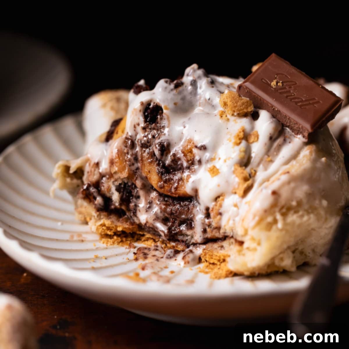 A smores roll on a white plate with bites missing to show the gooey texture.