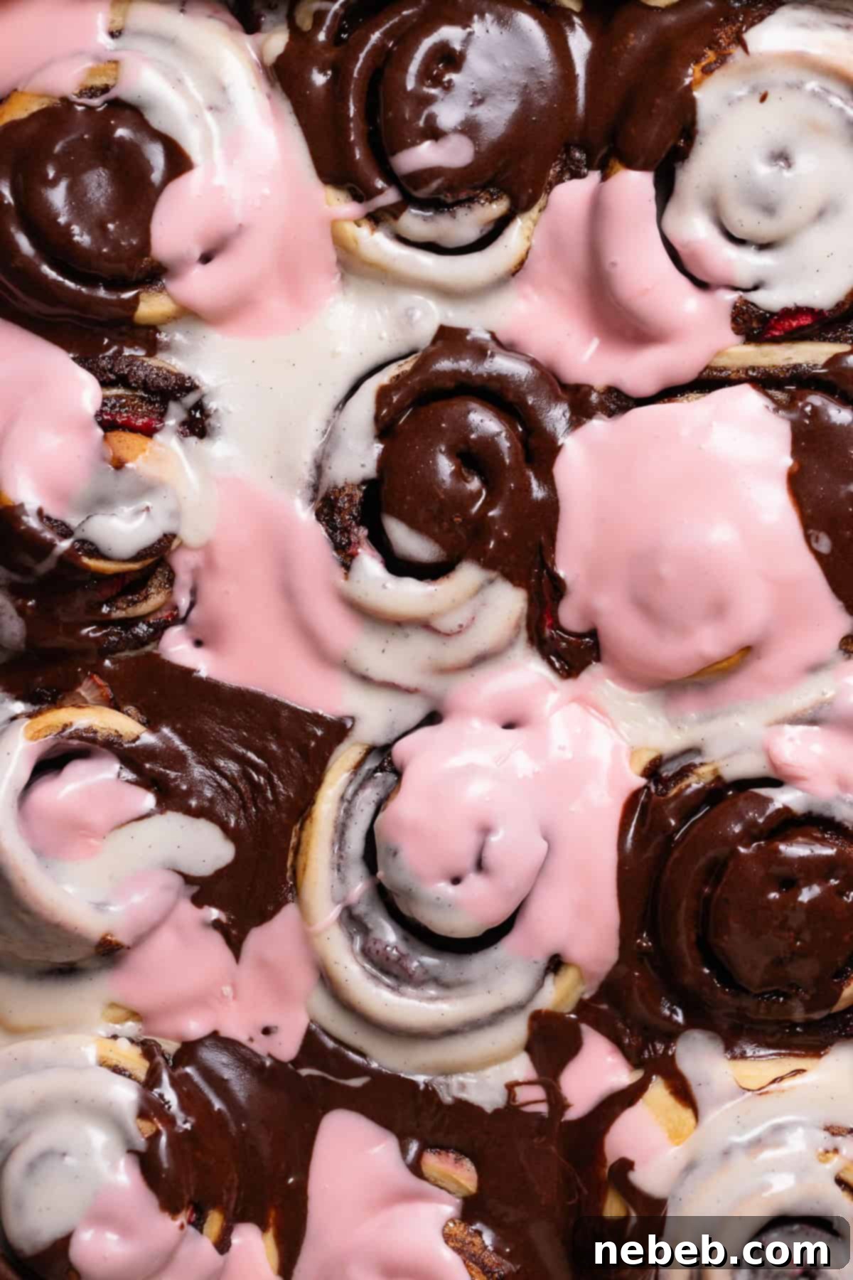 Neapolitan cinnamon rolls with pink, brown, and white marbled frosting, showcasing the classic chocolate, vanilla, and strawberry flavors.