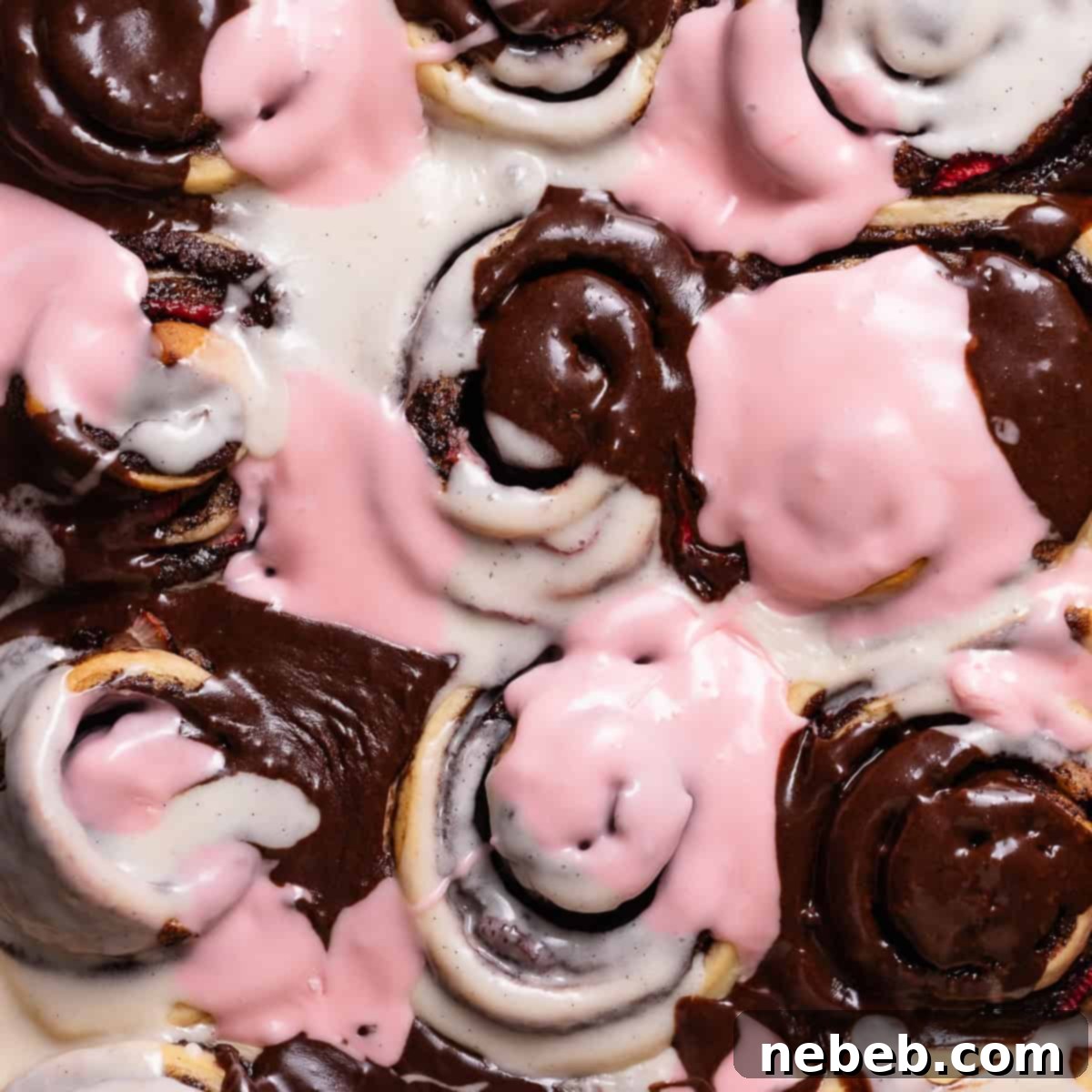 Neapolitan roll in a baking pan with tri-colored icing, a perfect blend of chocolate, vanilla, and strawberry.