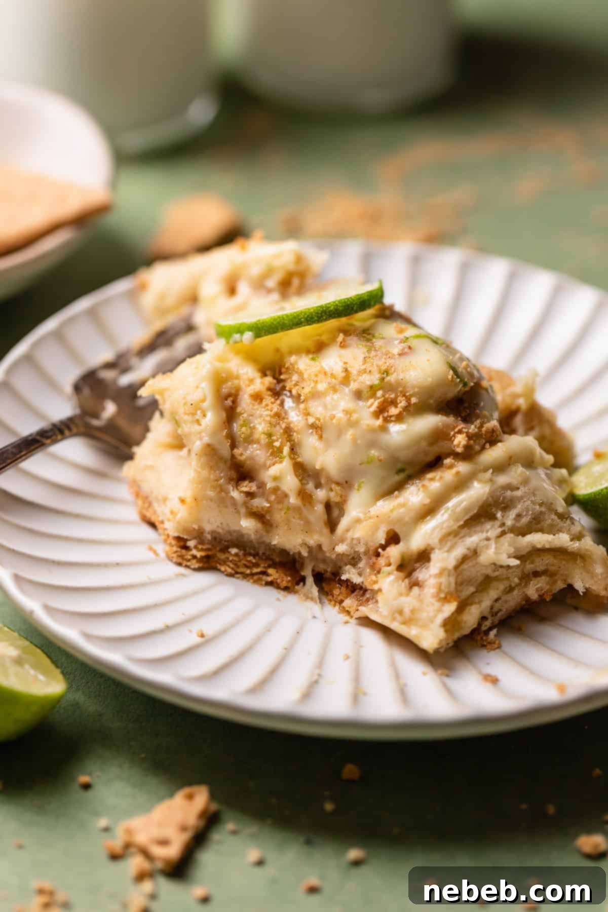 A key lime pie roll with a bite taken out of it on a white plate.