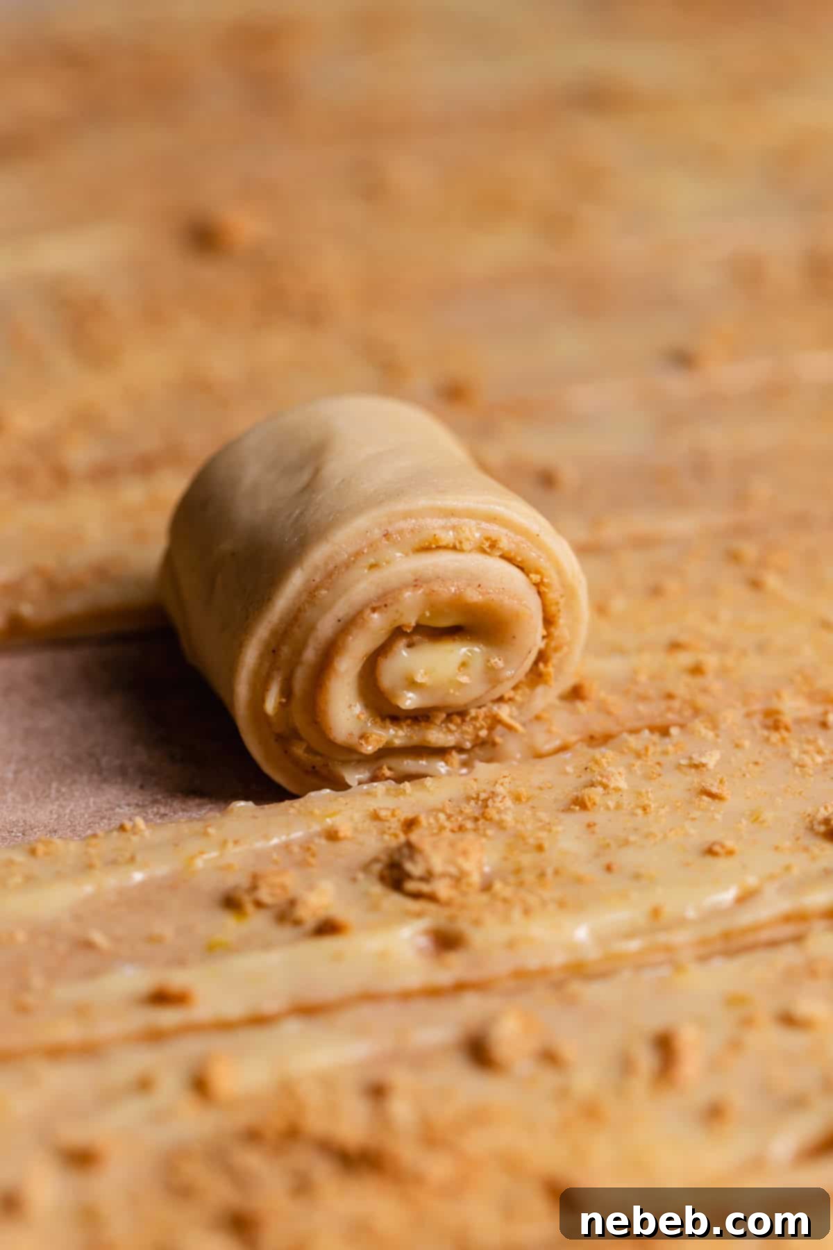 A strip of cinnamon roll dough being rolled up.