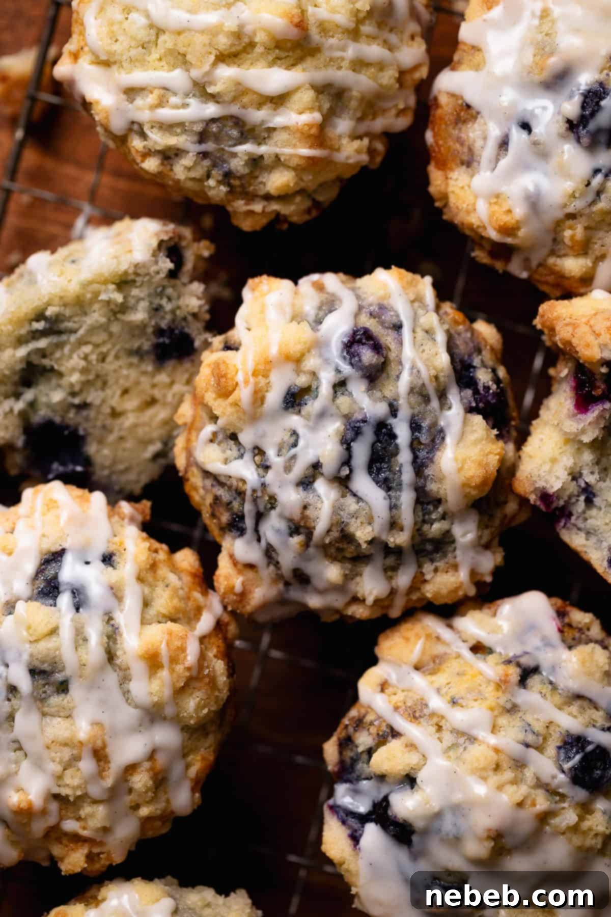 Crumb topped blueberry muffins with vanilla glaze on a rustic wooden board.