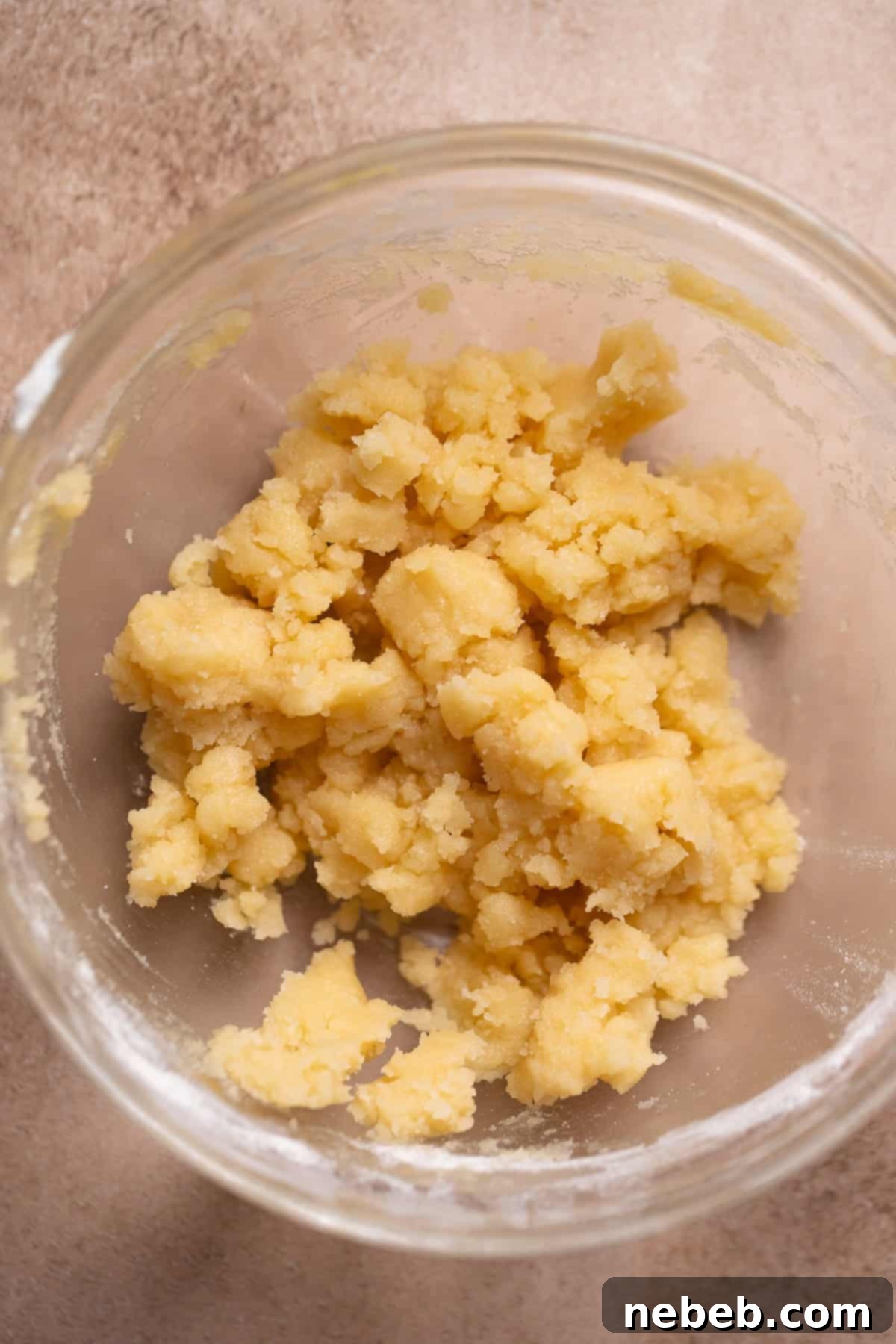 Crumb topping mixture in a glass mixing bowl, showing its crumbly texture.