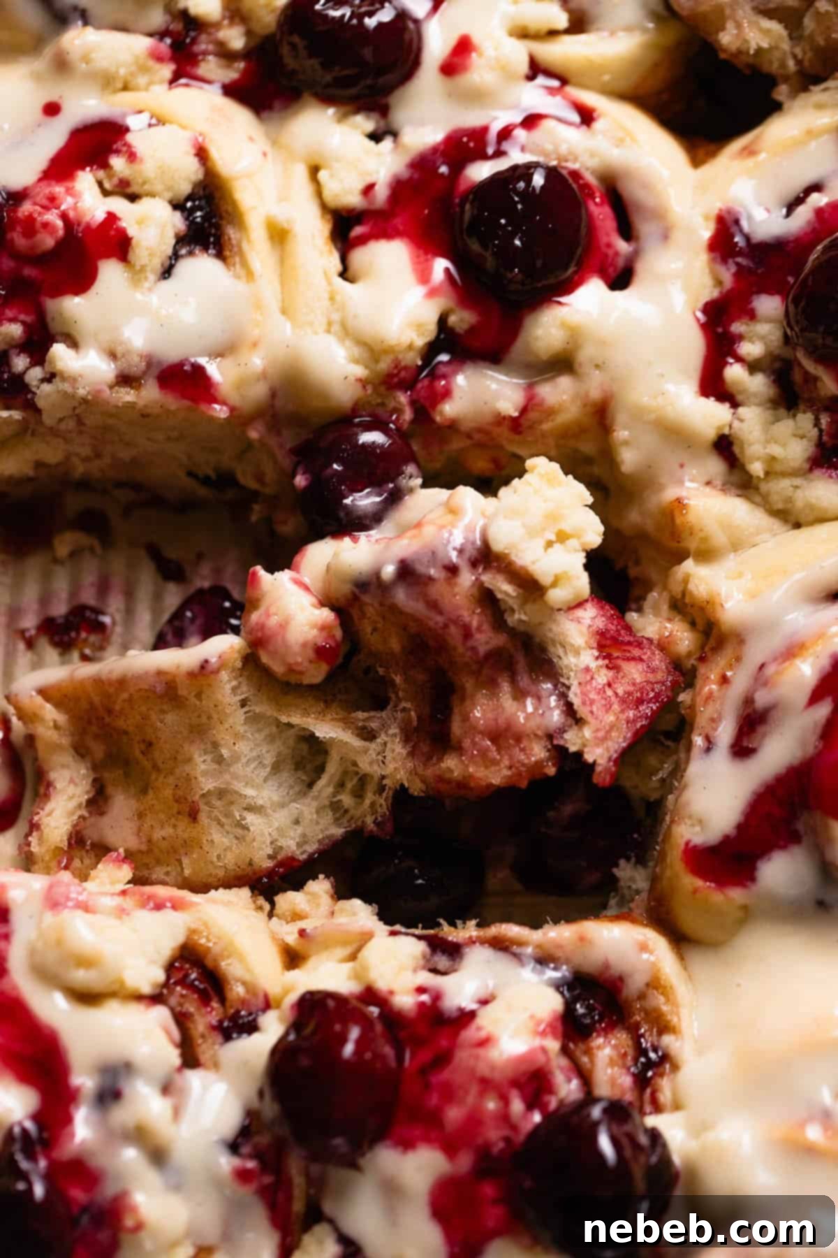 Overhead view of a cherry cinnamon roll being unrolled to show the gooey cherry filling.