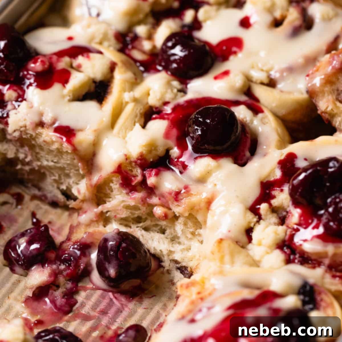 Close-up of cherry pie cinnamon rolls with swirls of cherry jam and pie crumb topping.