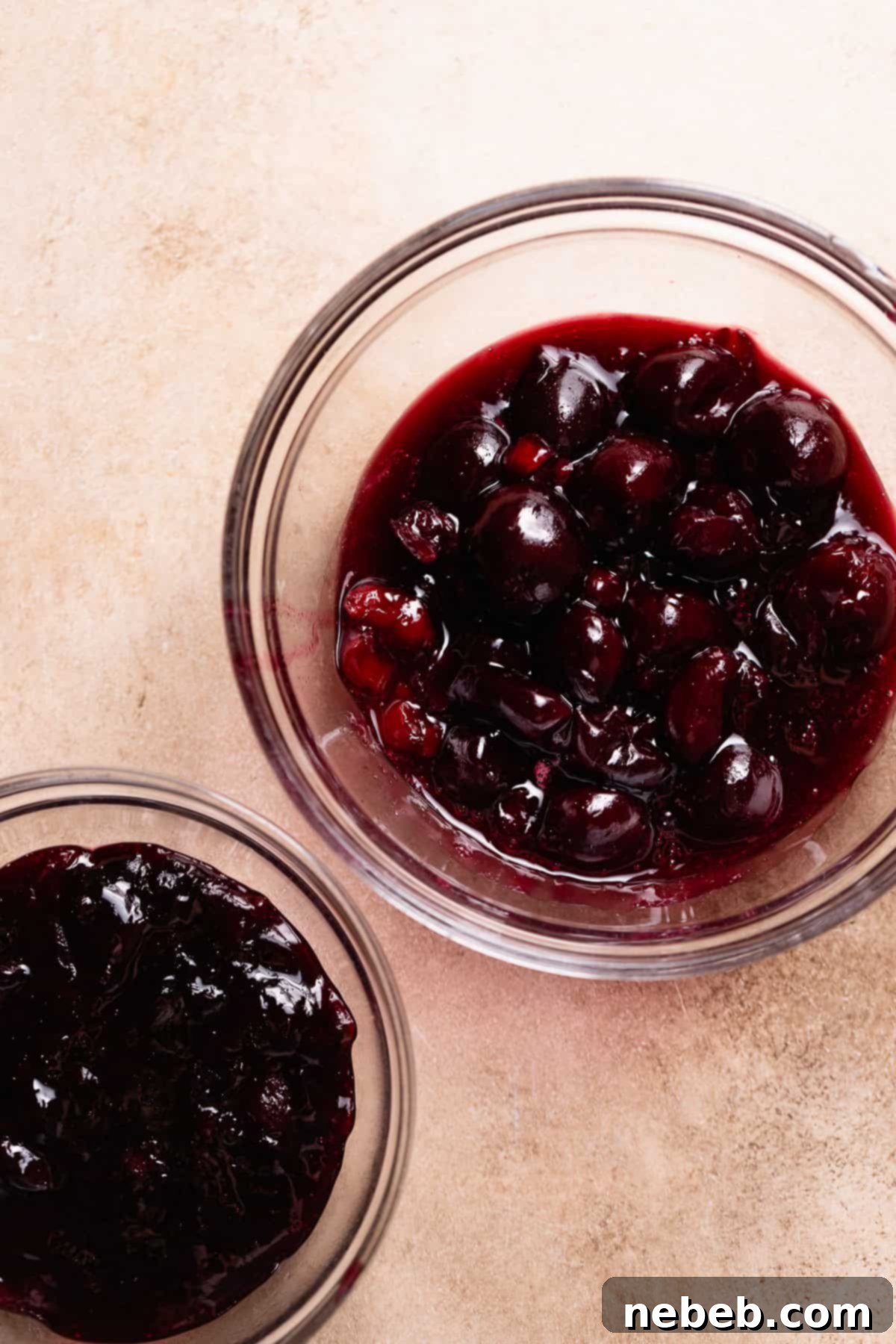 Two small bowls showing homemade cherry jam and cooked whole cherries for the cinnamon roll filling.