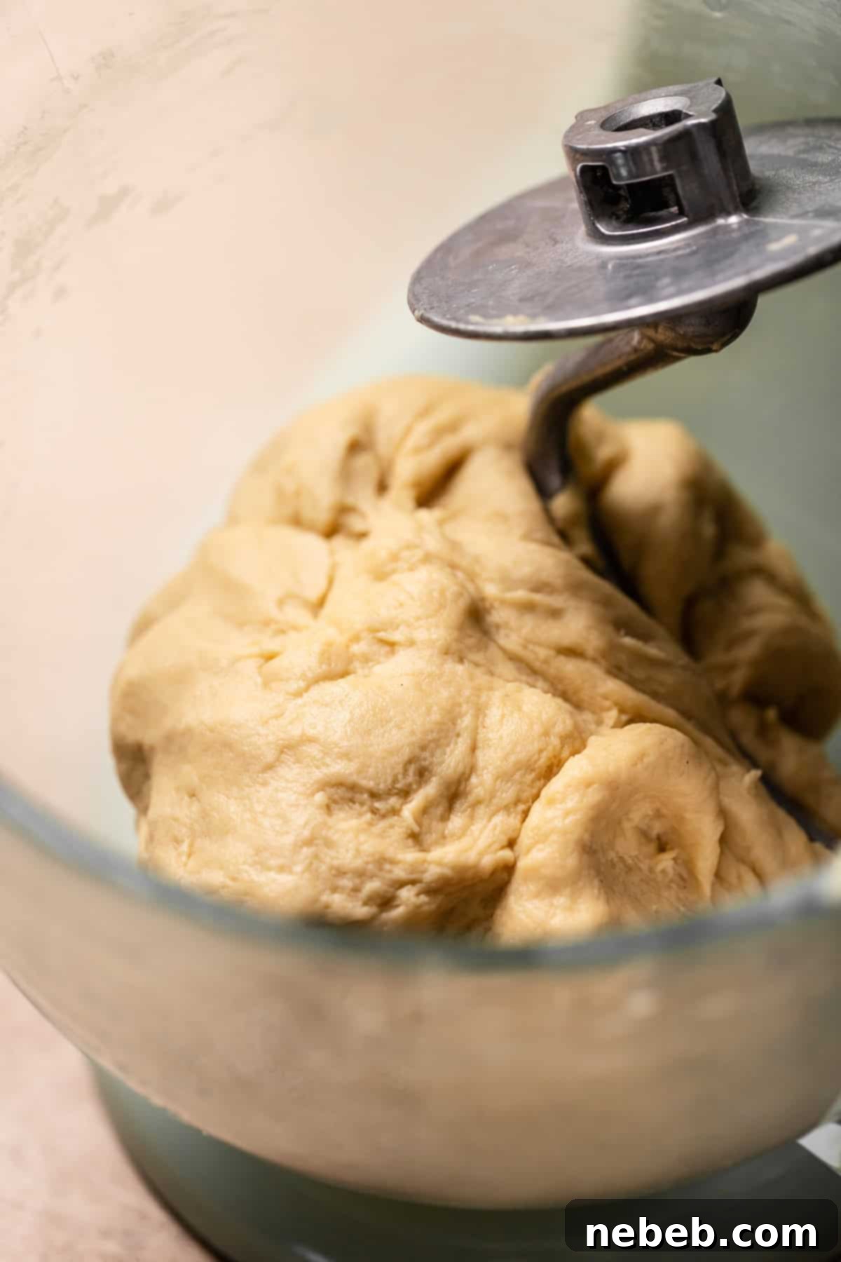 Smooth elastic cinnamon dough ball in glass mixer bowl.