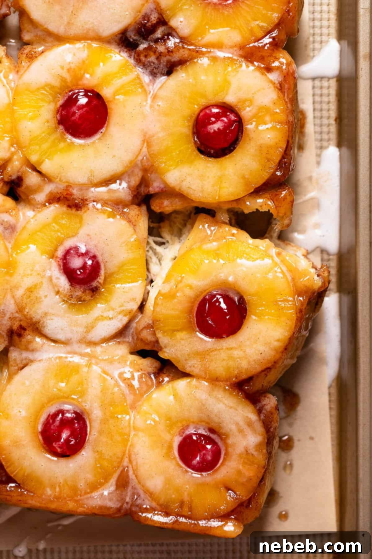 Pineapple upside down rolls on a baking pan drizzled with vanilla glaze.