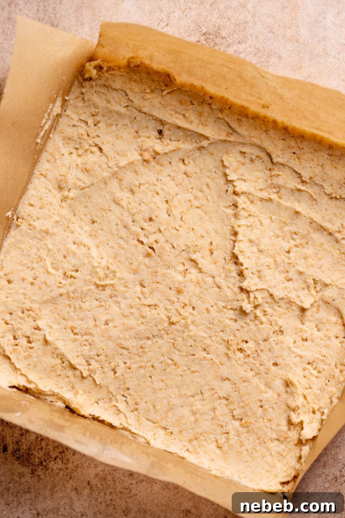 Graham cracker cookie dough spread onto parchment paper in a square shape.