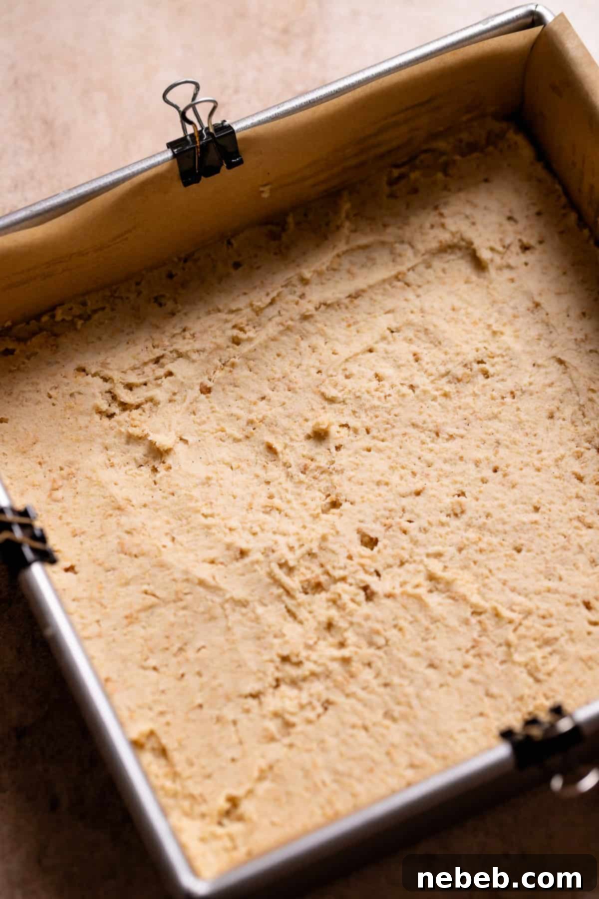 Graham cracker cookie dough spread into the bottom of a metal baking pan.
