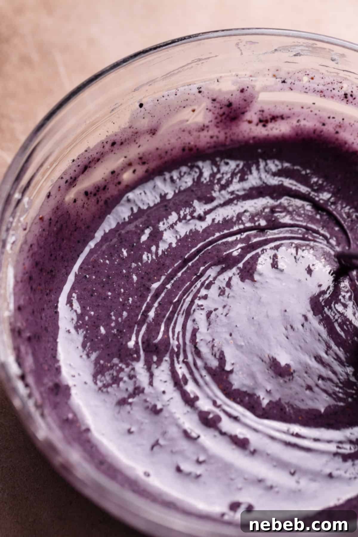 Blueberry donut glaze being whisked in a glass bowl.