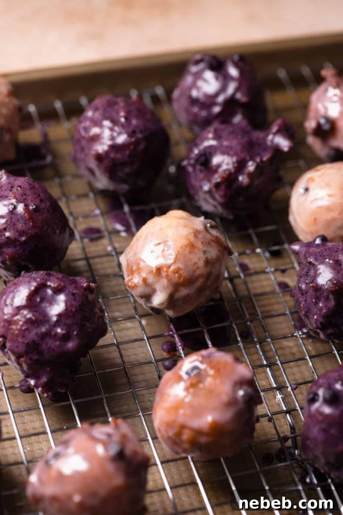 Mini blueberry glazed cake donuts on a wire rack tray.