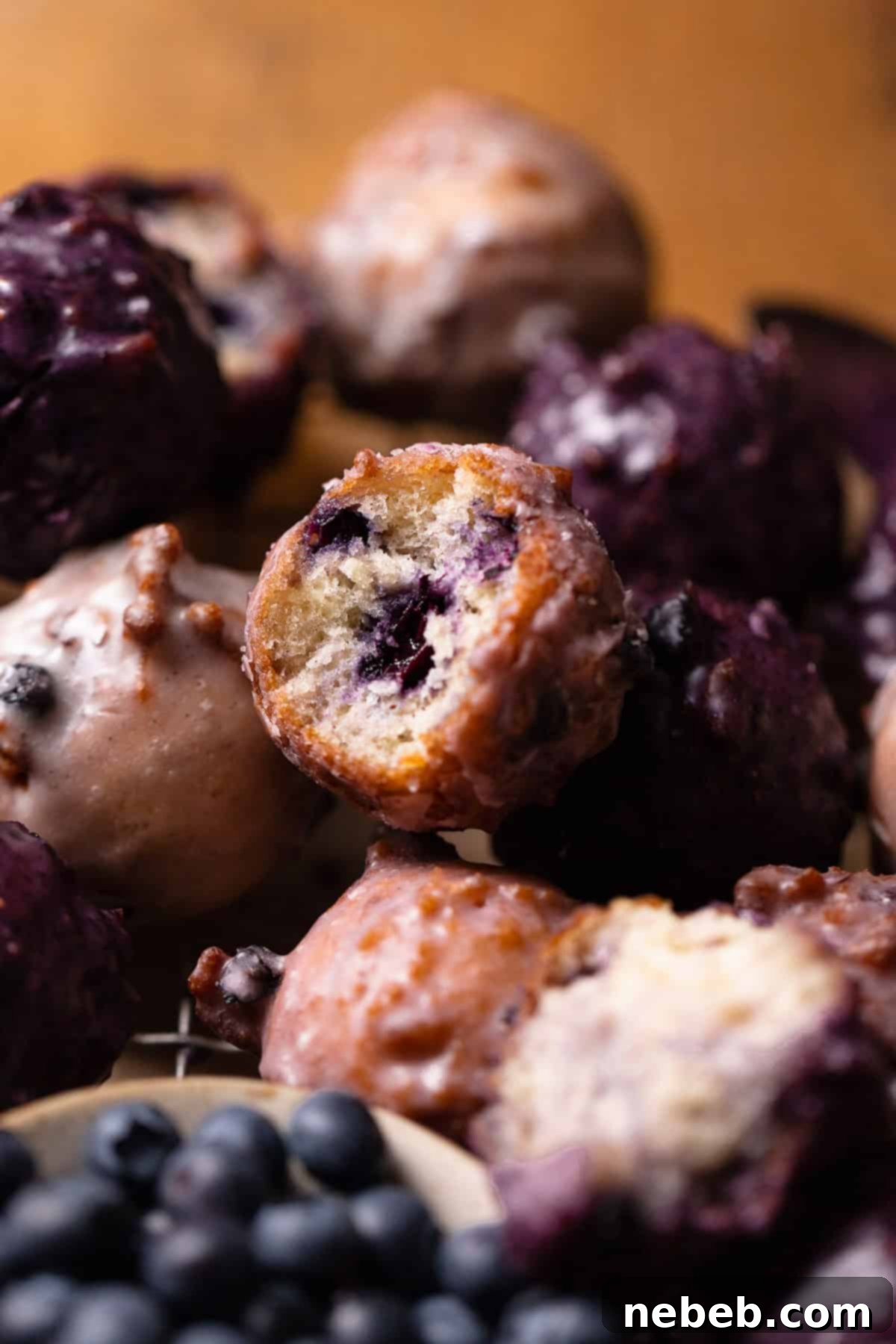 A mini blueberry donut with a bite missing in a stack of other donuts.