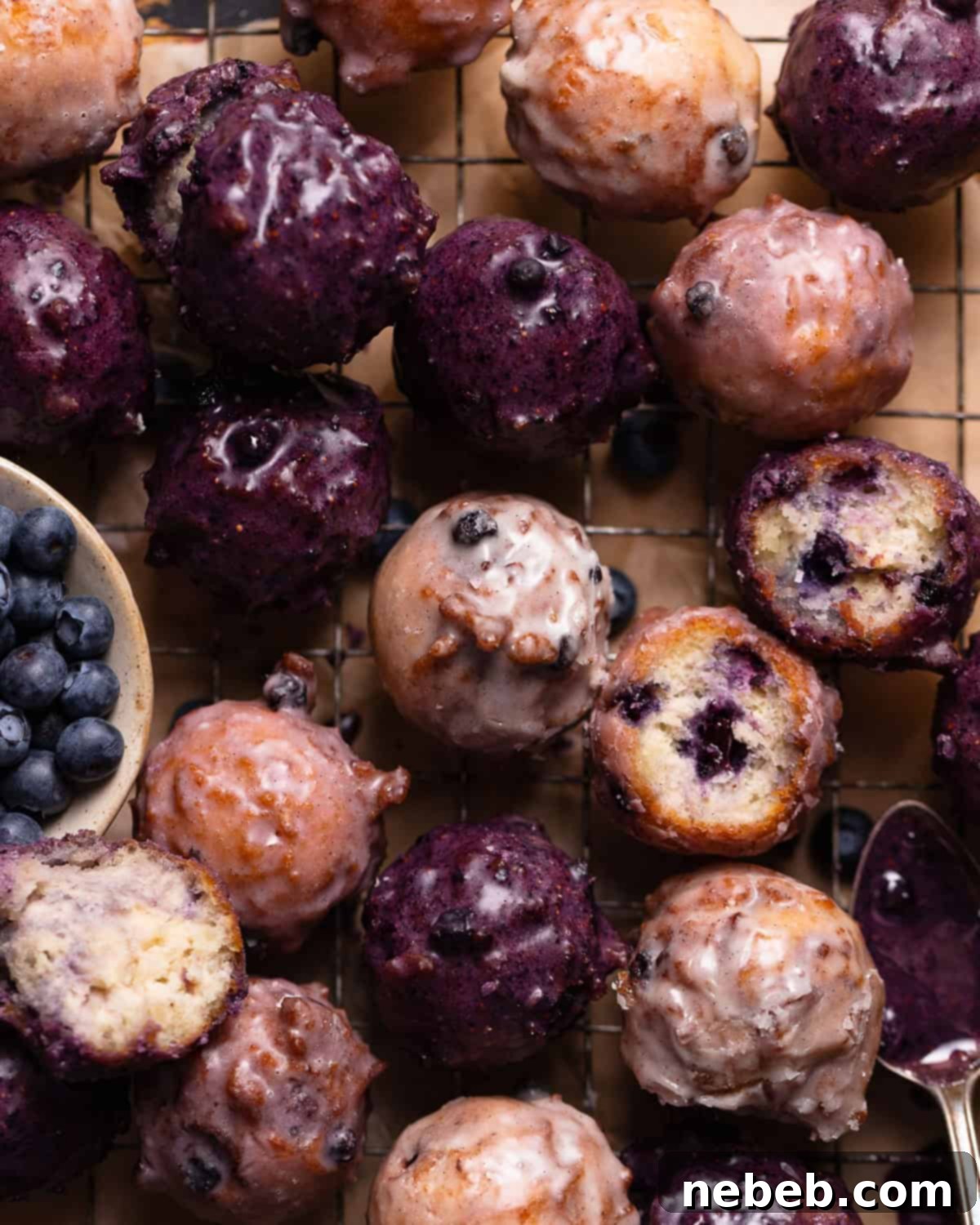 Close up shot of blueberry cake donuts with blueberry glaze on a wire rack.