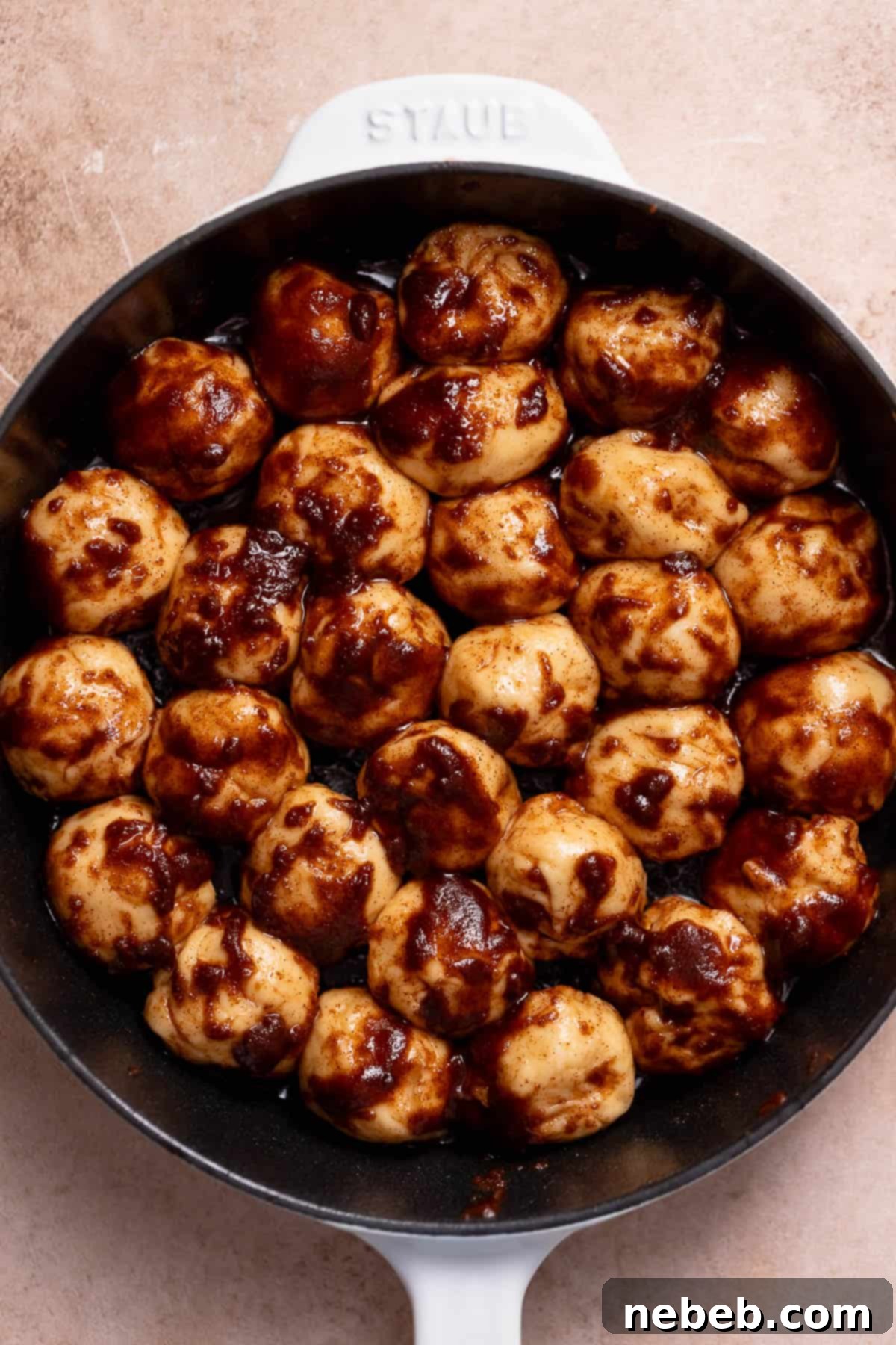 Monkey bread in a skillet covered in melted butter and cinnamon sugar.