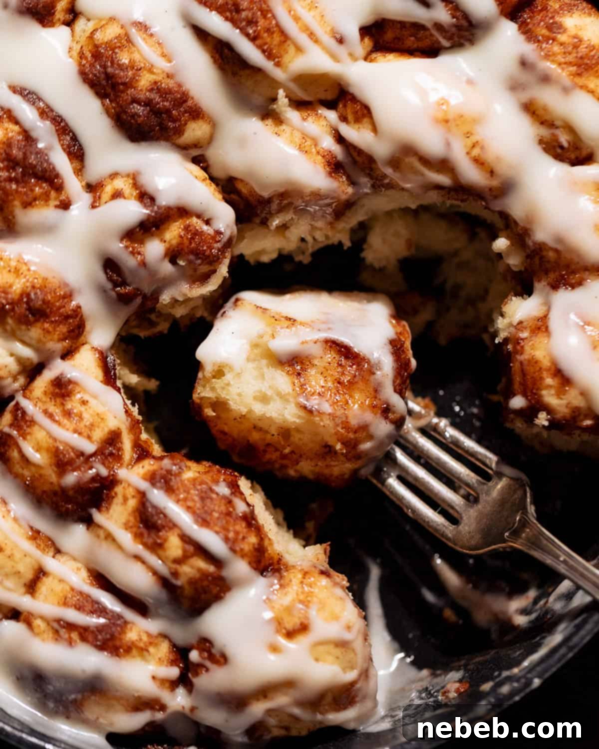 A bite of cinnamon roll monkey bread in a skillet on a fork.