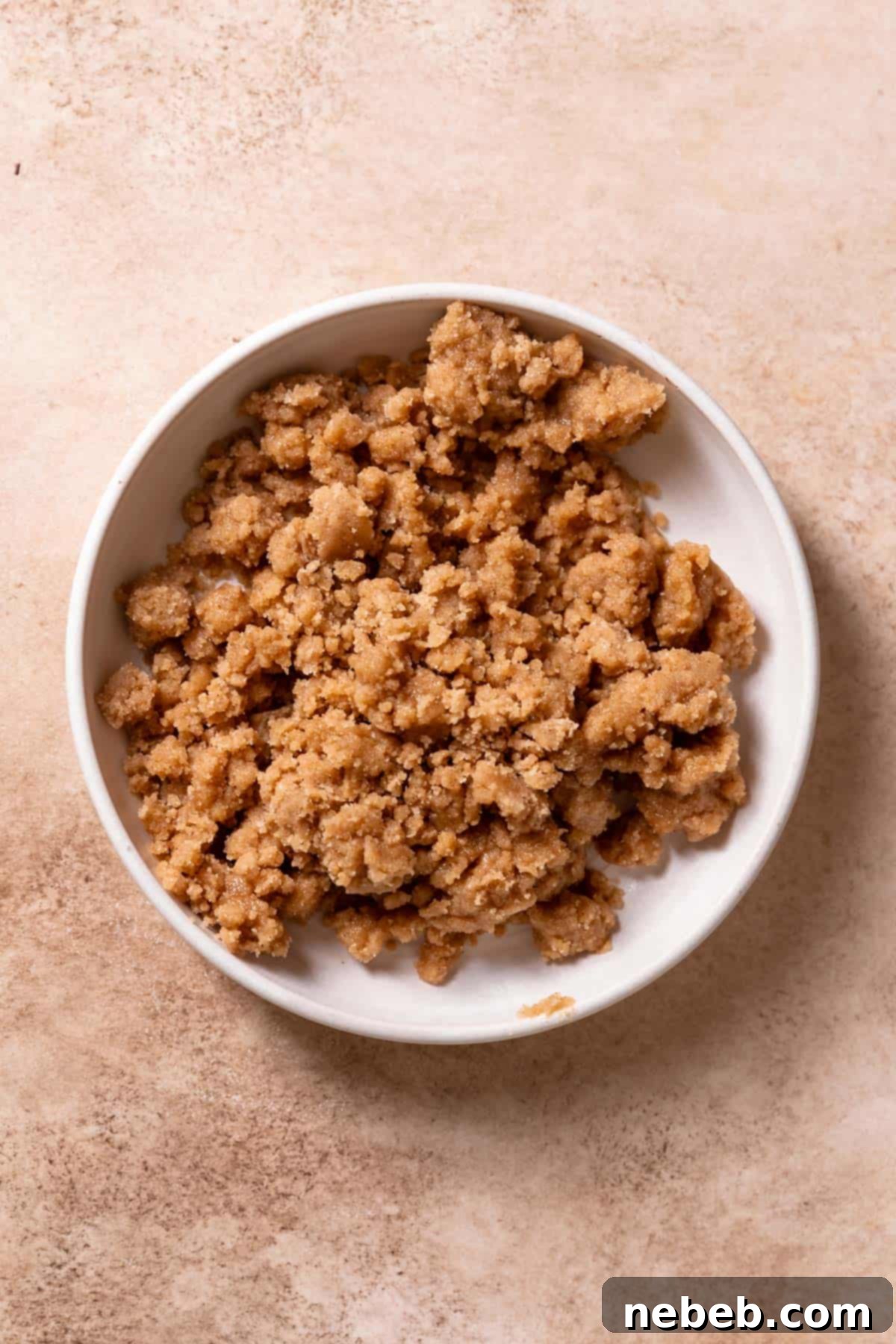 Best Ever Cinnamon Apple Cake 4 A white bowl filled with dense cinnamon crumb topping mixture, ready to be chilled.
