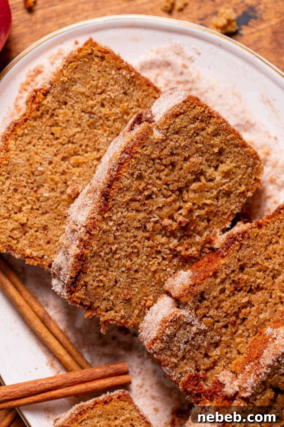 Slices of apple cider cake on a white plate surrounded by cinnamon sugar.