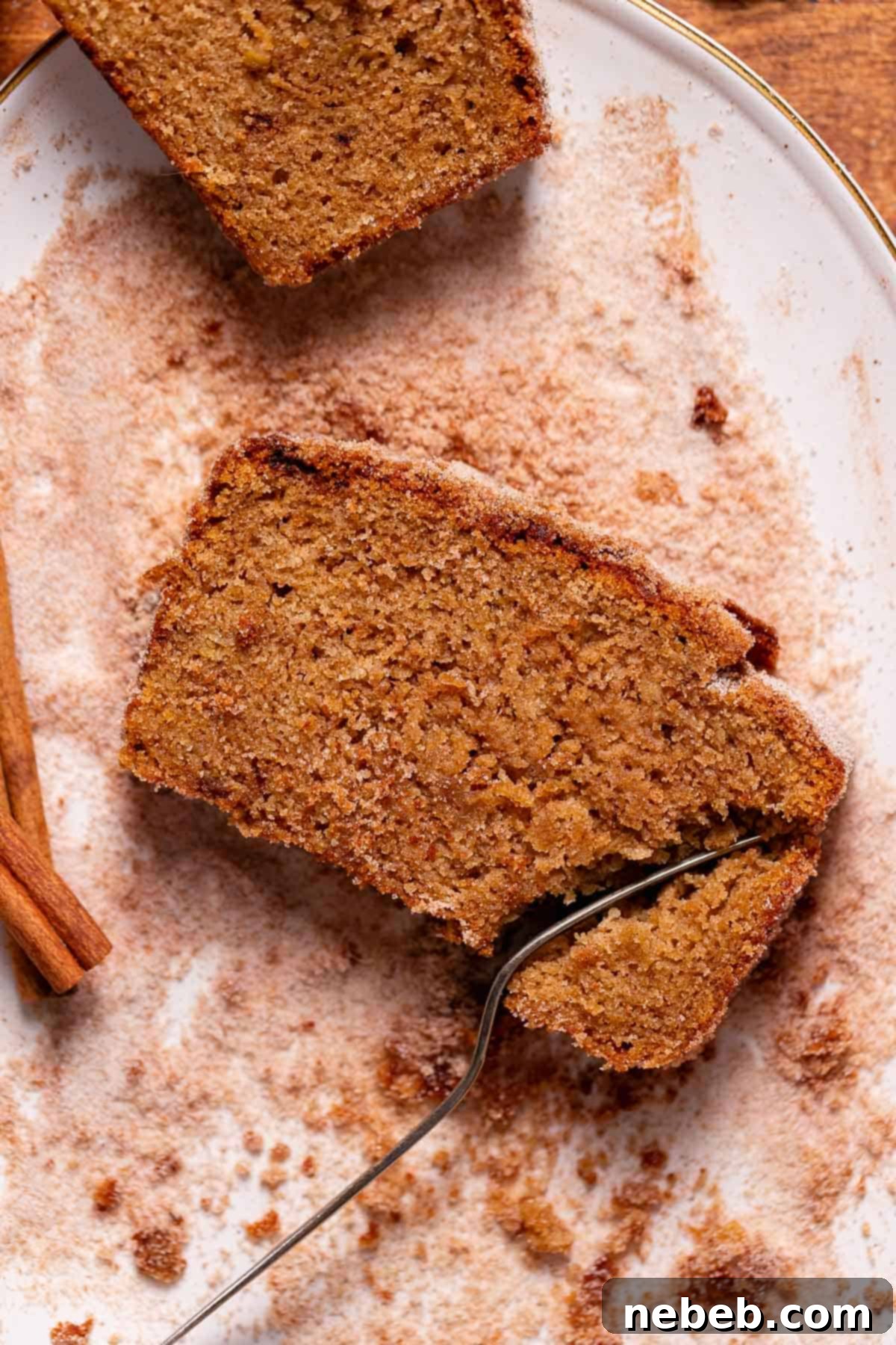 A slice of apple cider loaf being cut into with a fork.
