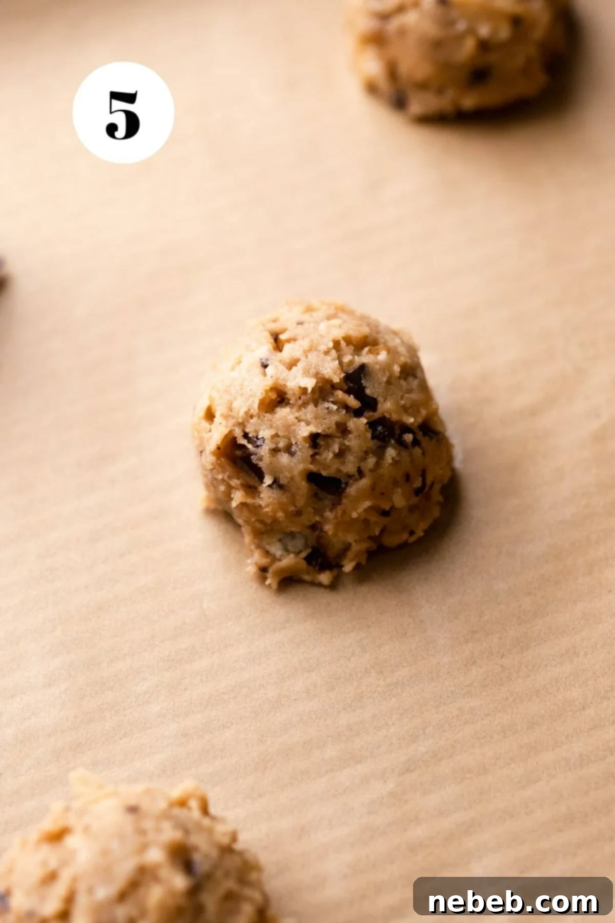 A few perfectly scooped cookie dough balls arranged on a parchment-lined baking tray, ready for baking.