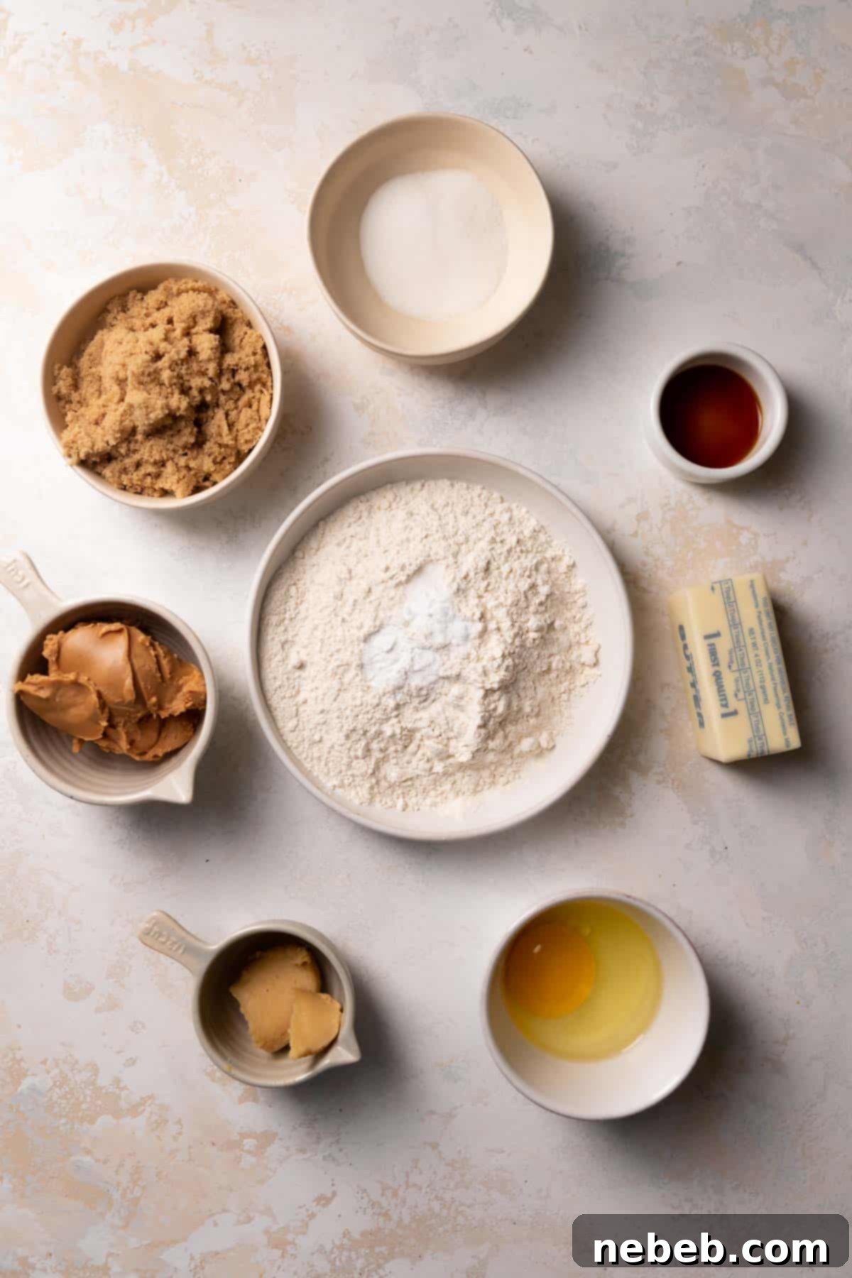 Ingredients needed to make peanut butter cookies in bowls with labels.