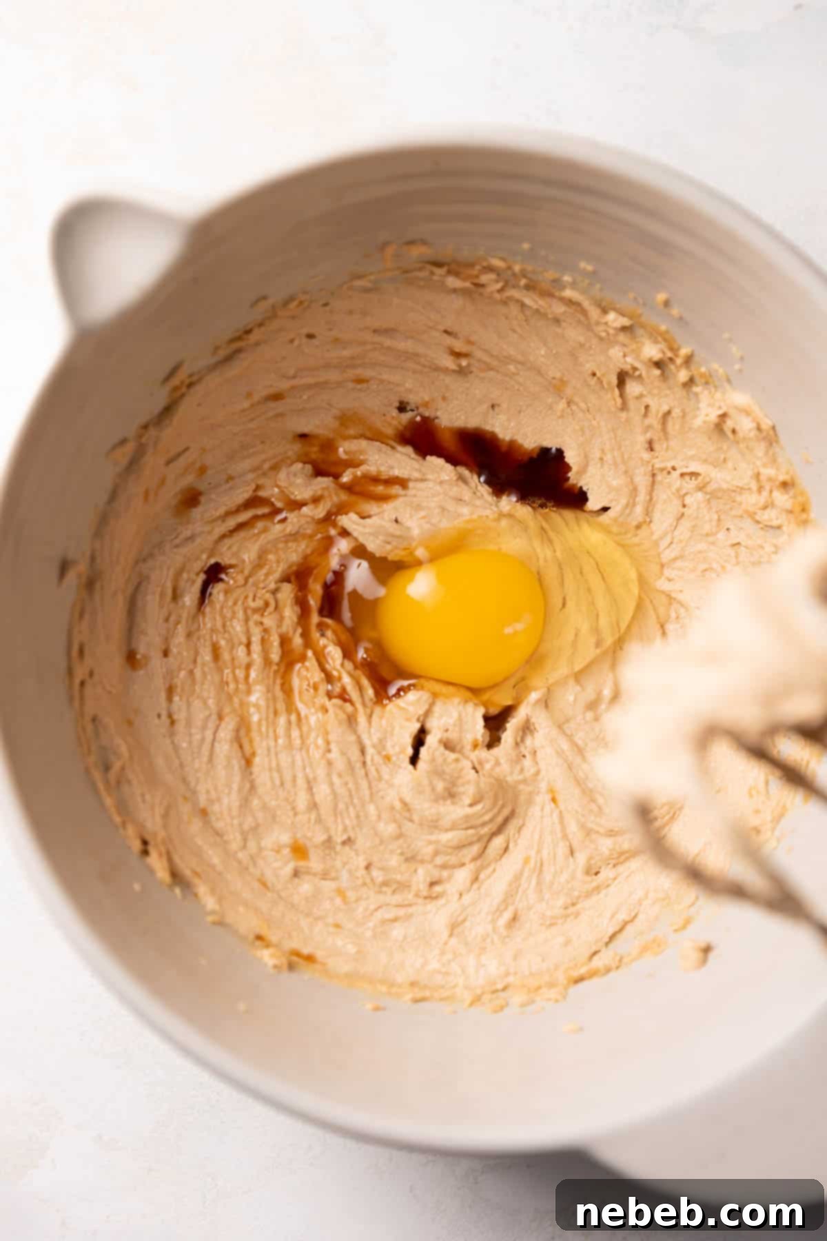 A mixing bowl with the creamed butter with egg and vanilla on top.