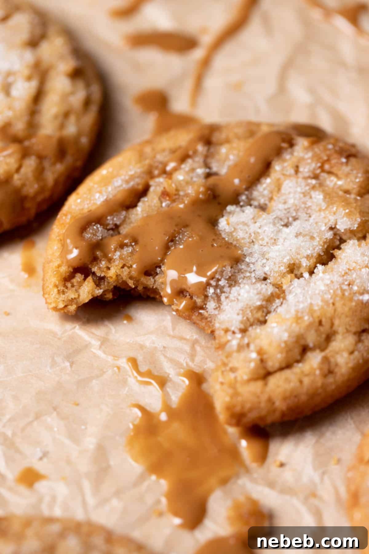 Peanut butter cookie with a bite taken out of it on parchment paper.