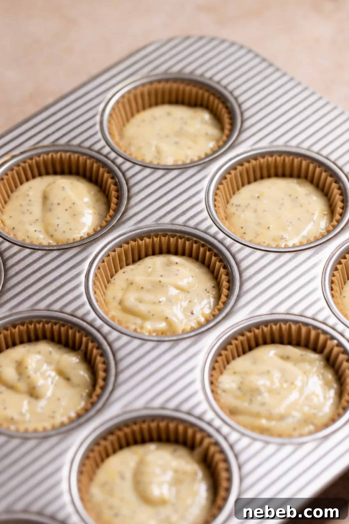 Lemon cupcake batter meticulously scooped into cupcake liners before baking.