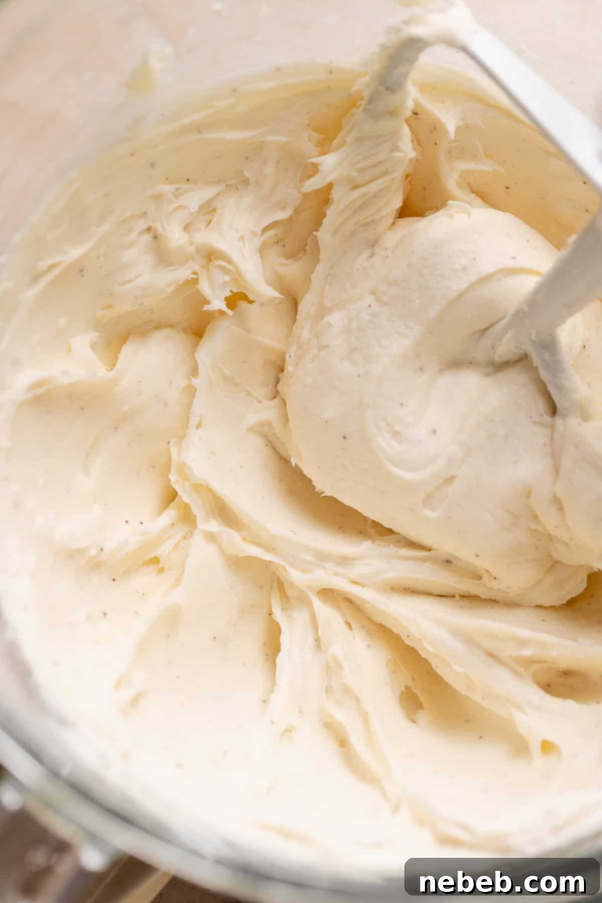 A bowl of freshly made, smooth cream cheese frosting, ready to be piped onto cupcakes.
