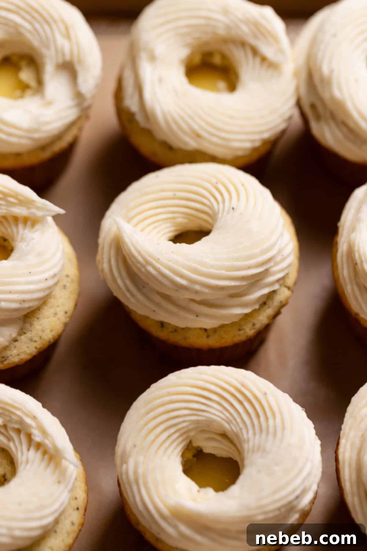 Baked lemon cupcakes beautifully topped with piped cream cheese frosting, creating an elegant swirl.
