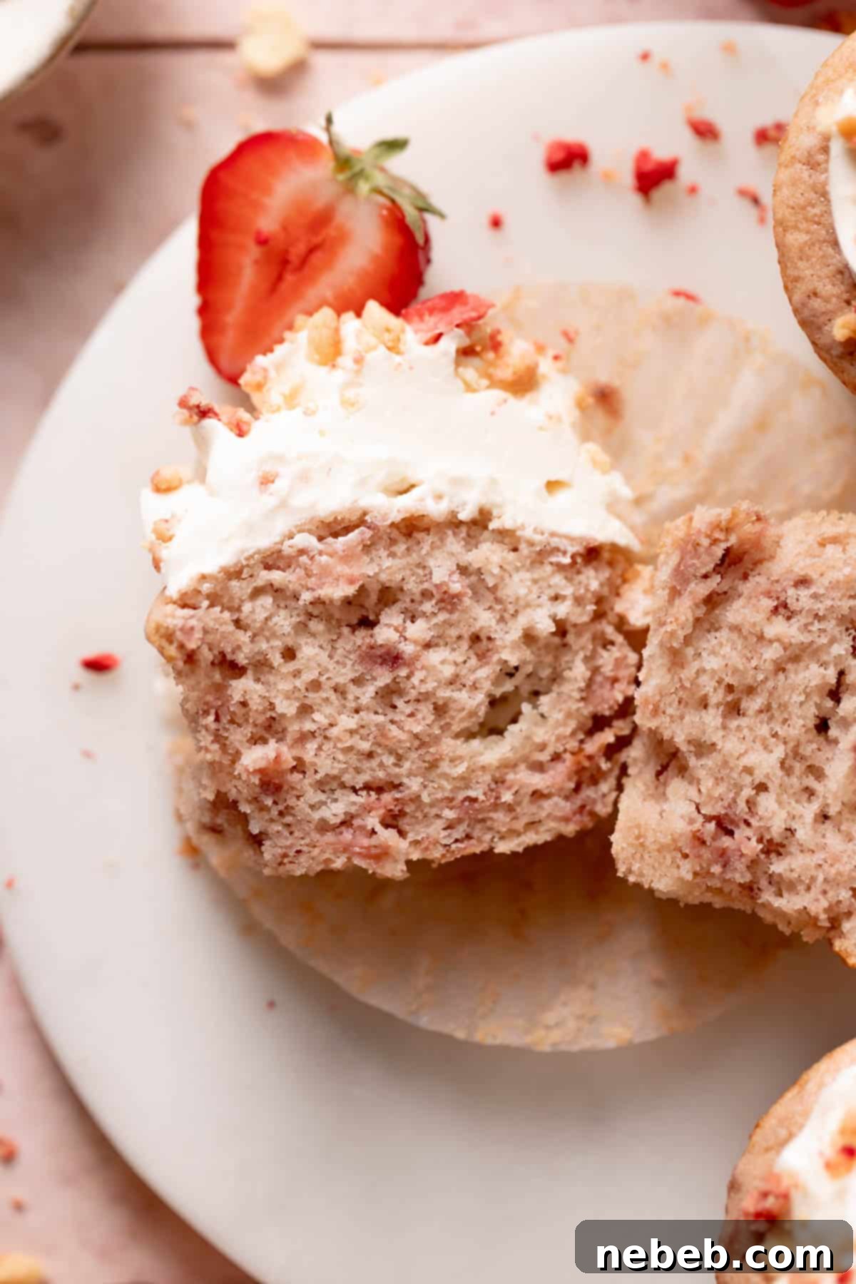 Golden Crunch Strawberry Cupcakes 11 Strawberry shortcake cupcake cut in half on a white plate, showcasing the moist roasted strawberry interior, vanilla frosting, and crunchy topping.