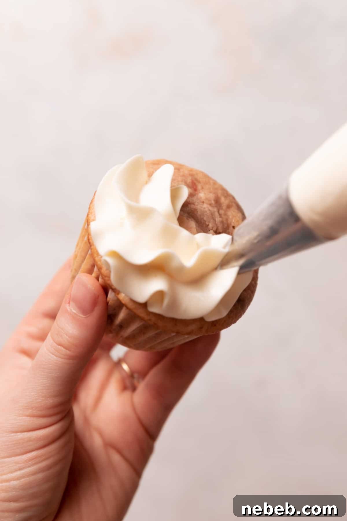 Golden Crunch Strawberry Cupcakes 10 Piping a perfect swirl of vanilla frosting on top of a cooled strawberry crunch cupcake.