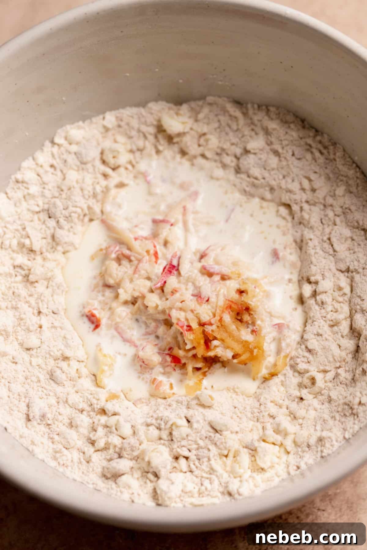 The bowl of scone dough with the cream and grated apples in the center.