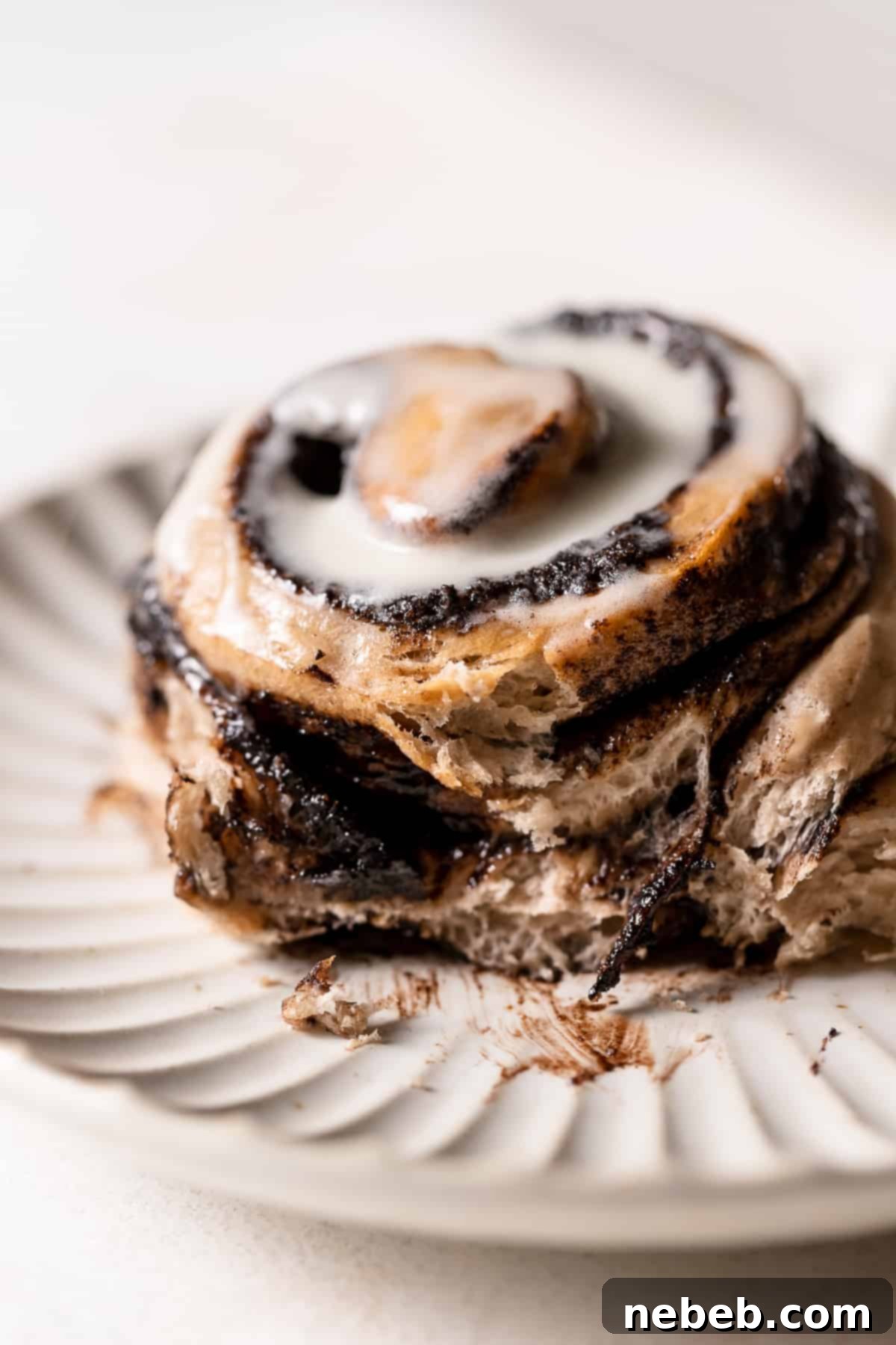 Oreo cinnamon roll on a plate with some of the chocolate filling oozing out, showcasing the rich filling and soft dough.