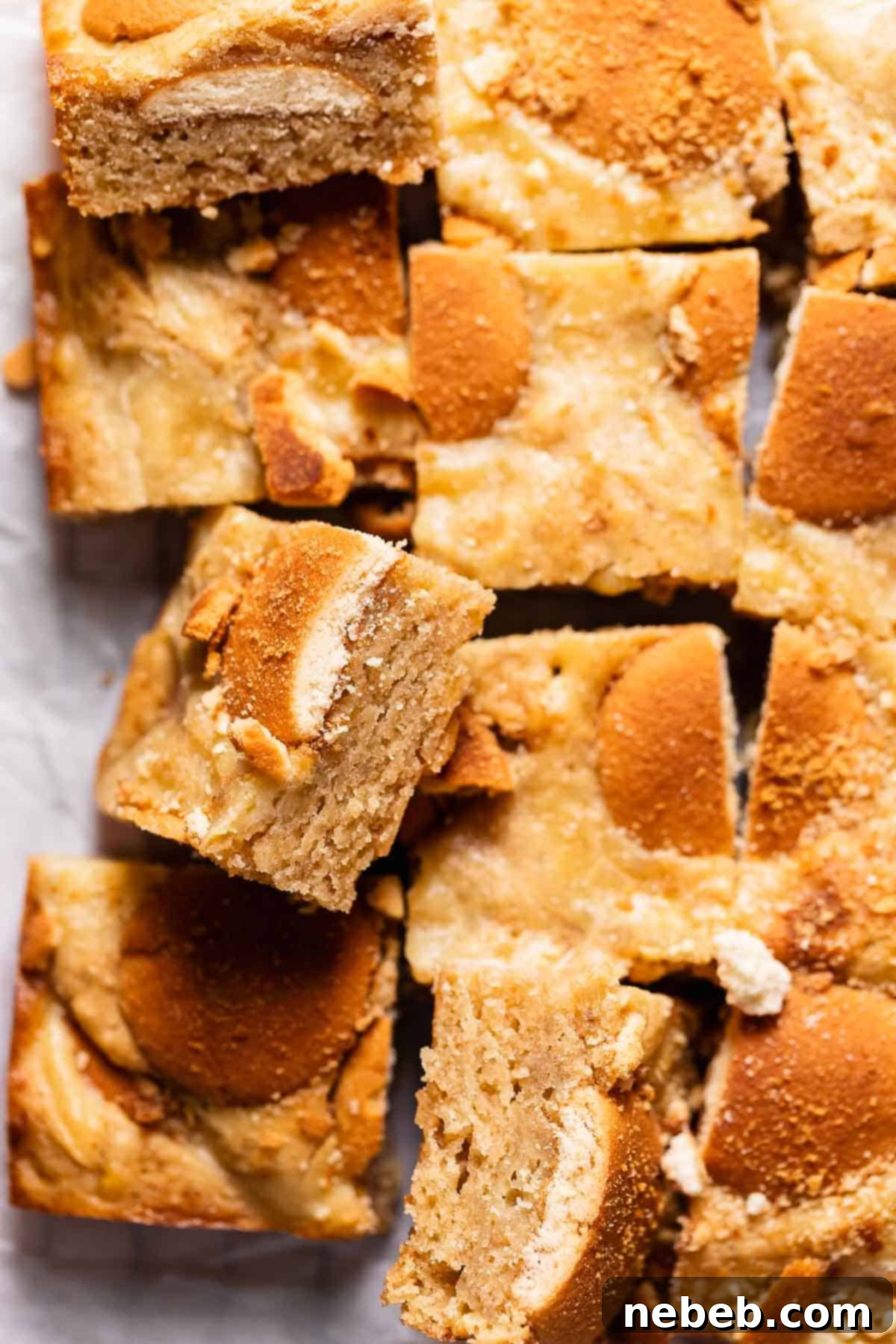 Banana pudding brownies with nilla wafers on top on white parchment paper.