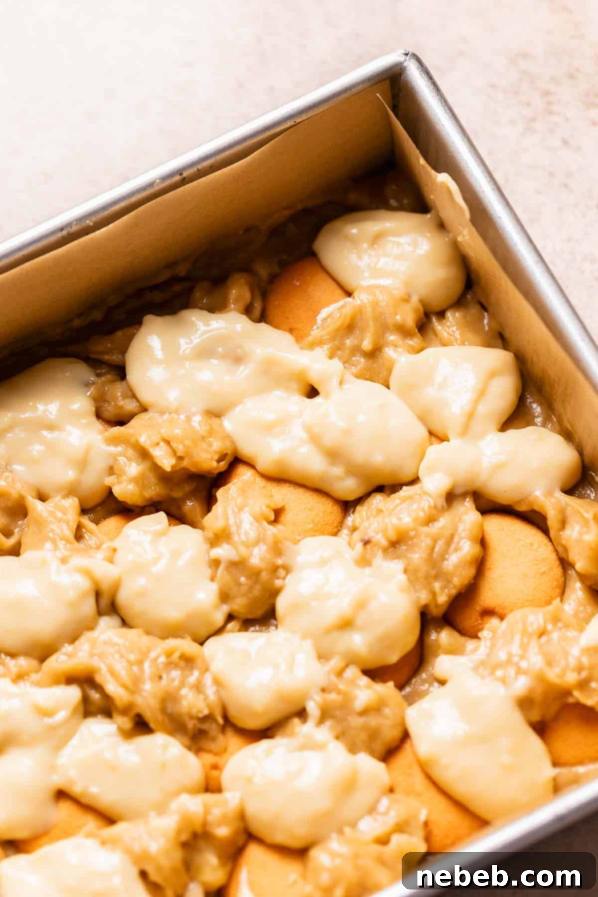 A baking pan with the layered pudding, cookies, and banana batter in it.