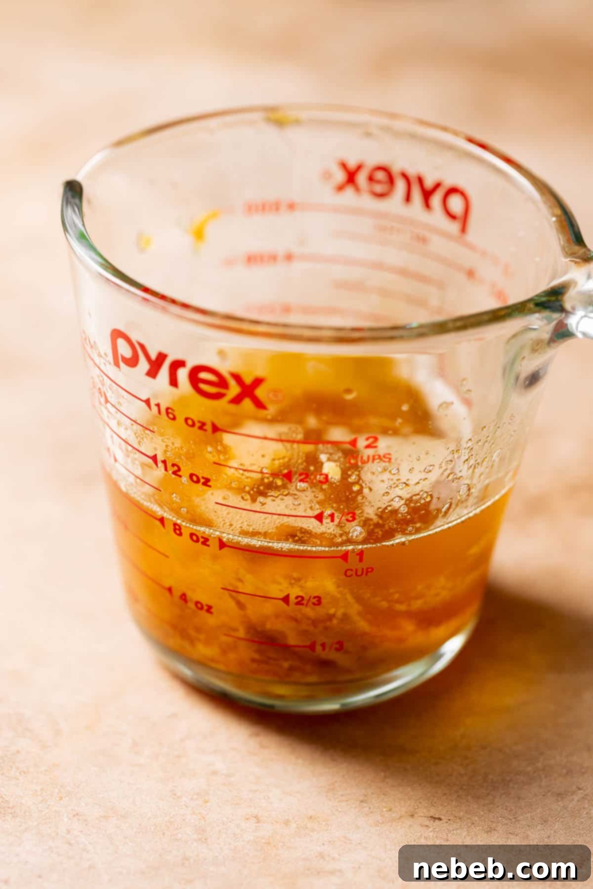 A glass measuring cup with the brown butter and miso paste.