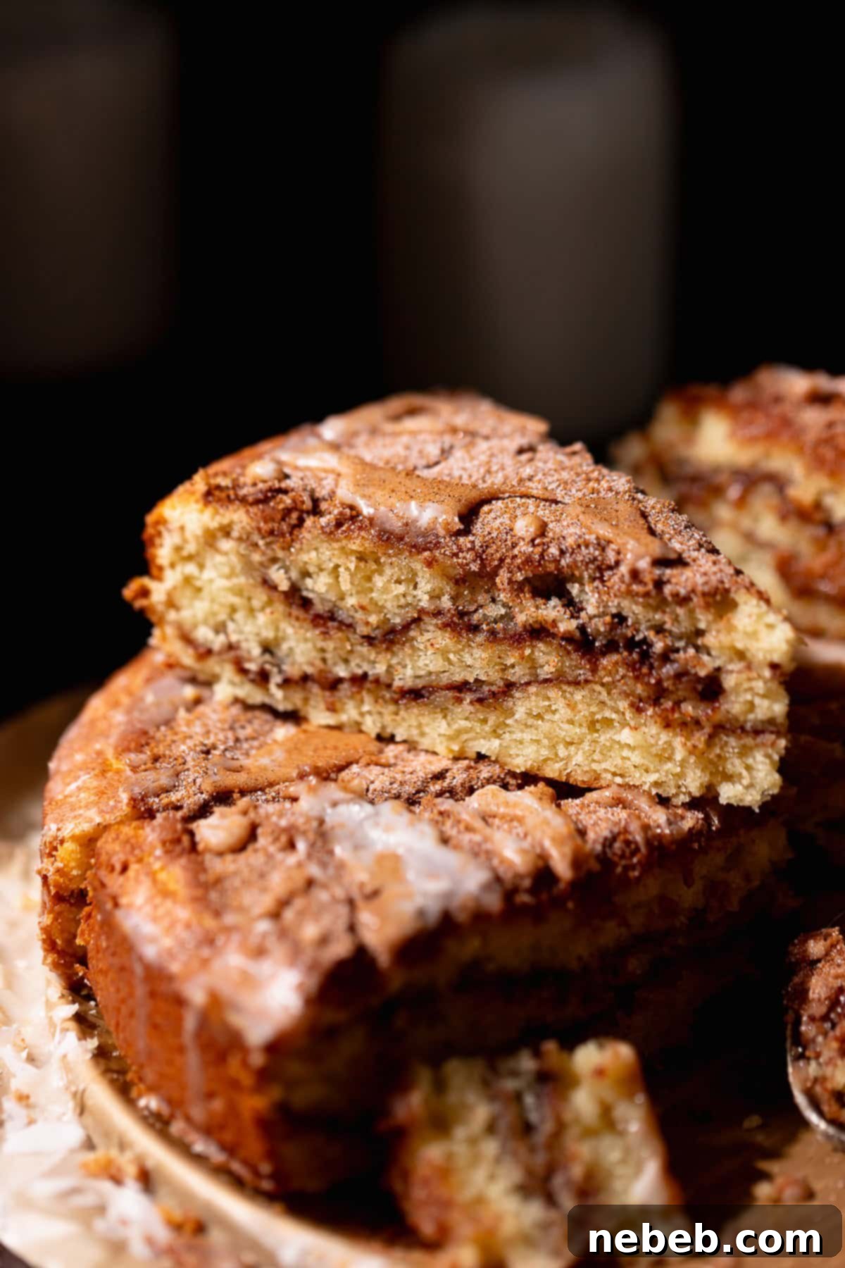 A slice of cinnamon coffee cake stacked on top of others to show the brown sugar cinnamon swirls.
