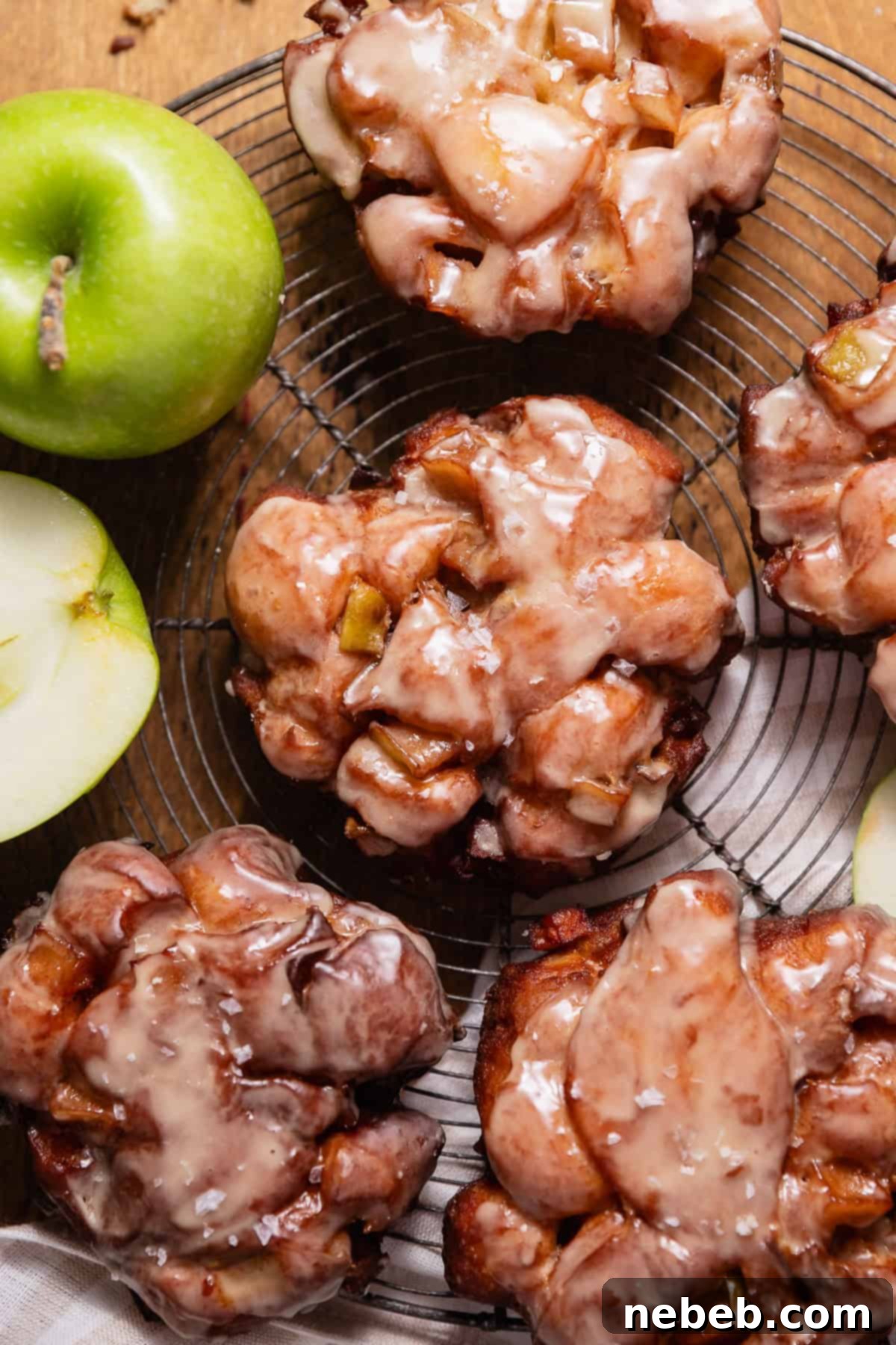 Homemade Apple Fritters So Good You Will Skip The Bakery 2 Glazed apple fritters sprinkled with flaky sea salt on a wire cooling rack.