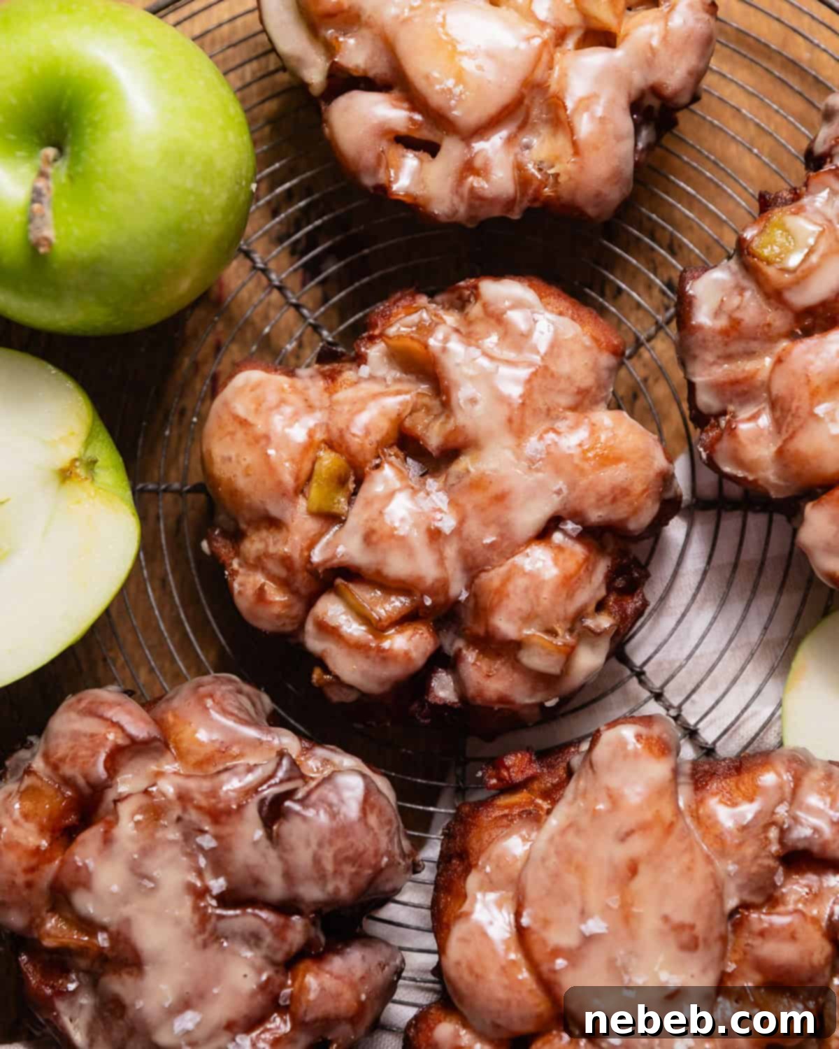 Homemade Apple Fritters So Good You Will Skip The Bakery 12 Deep fried apple fritters with apple cider glaze on a wire cooling rack.