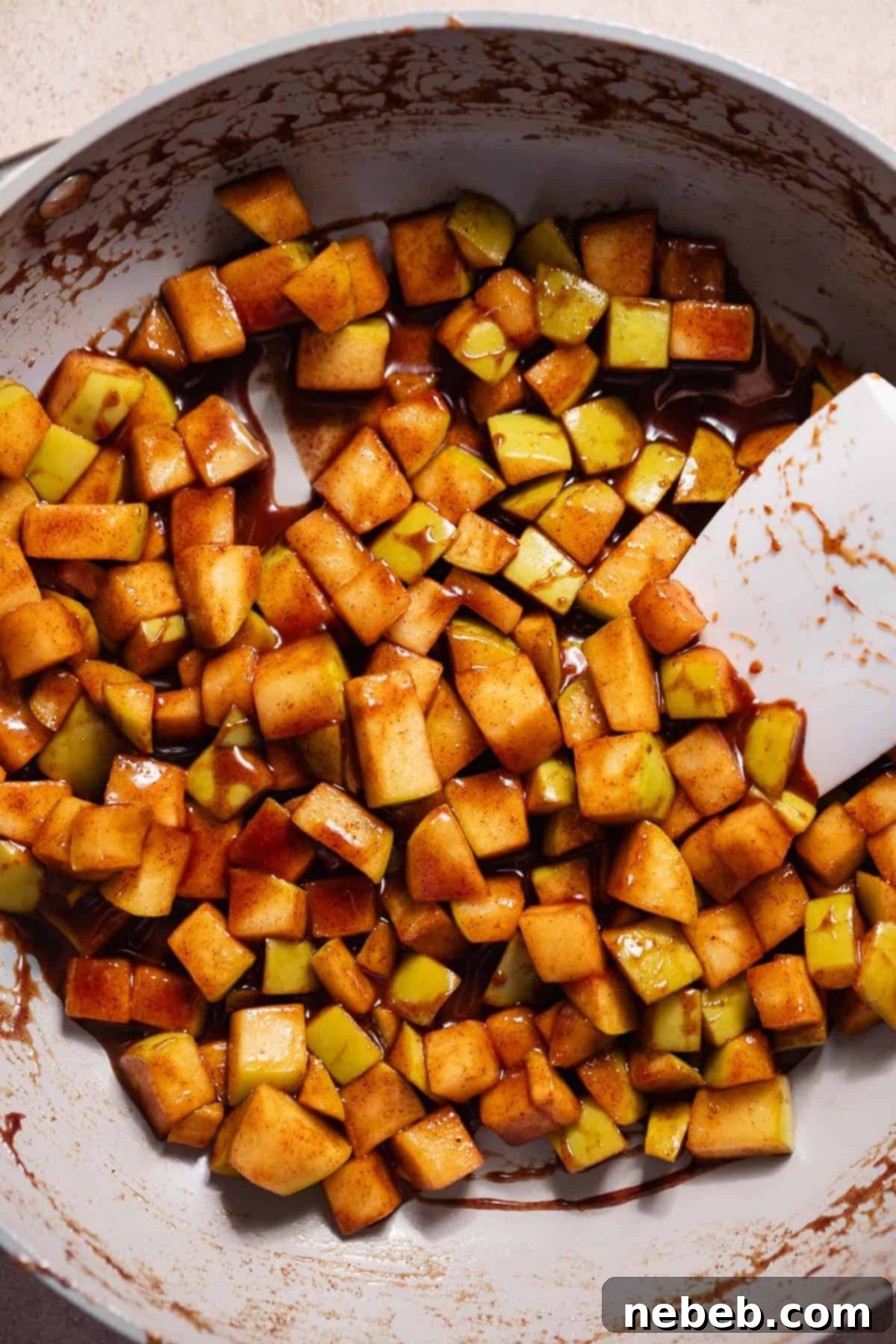 Homemade Apple Fritters So Good You Will Skip The Bakery 3 Cooked cinnamon sugar apples in a pan being stirred with a spatula.