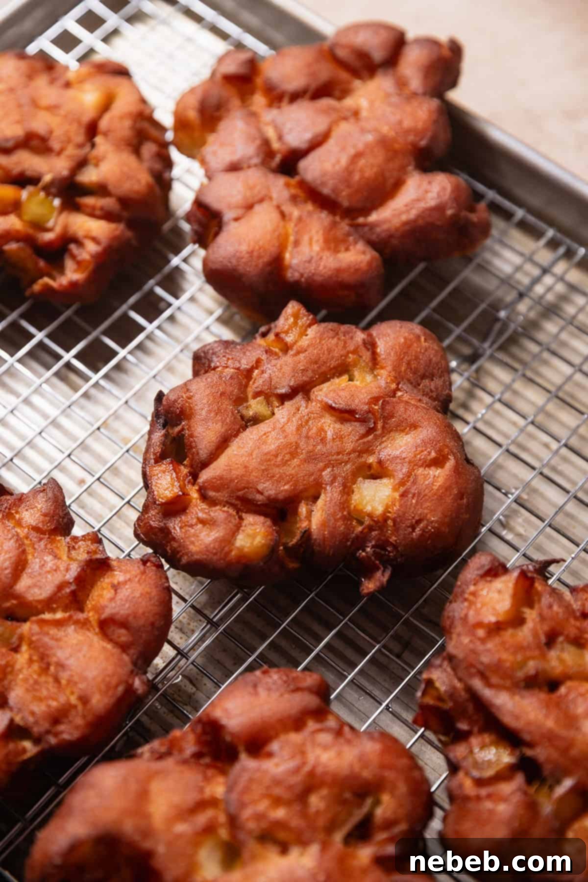 Homemade Apple Fritters So Good You Will Skip The Bakery 10 Deep fried apple fritters cooling on a wire rack.