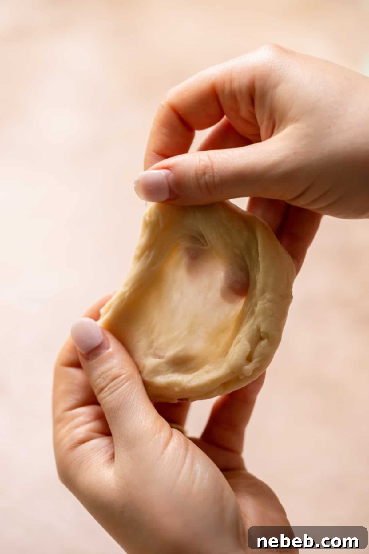 Glistening Salted Caramel Doughnuts 5 Two hands stretching the donut dough to show the strong gluten windowpane.