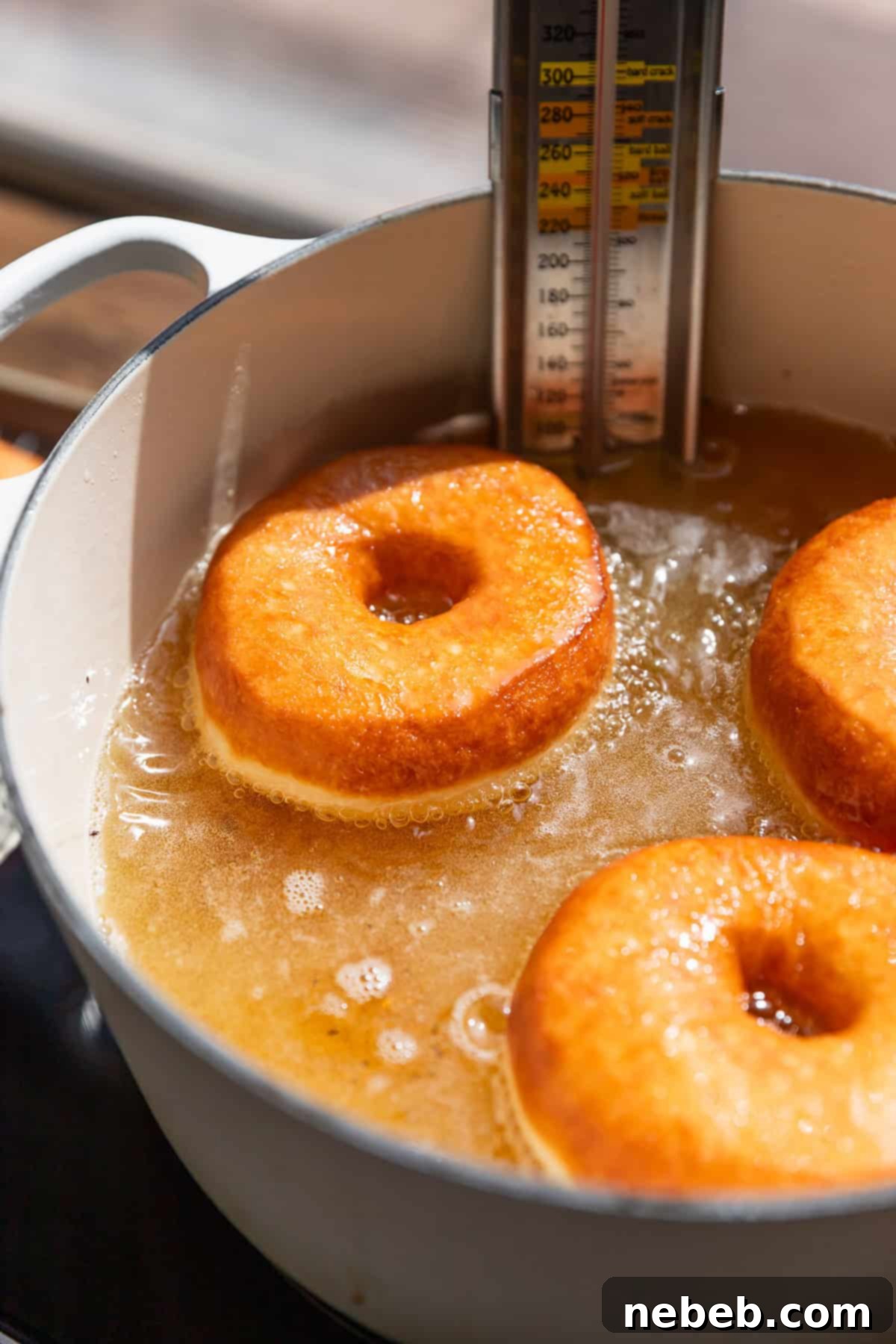 Glistening Salted Caramel Doughnuts 8 Three donuts frying in hot oil.