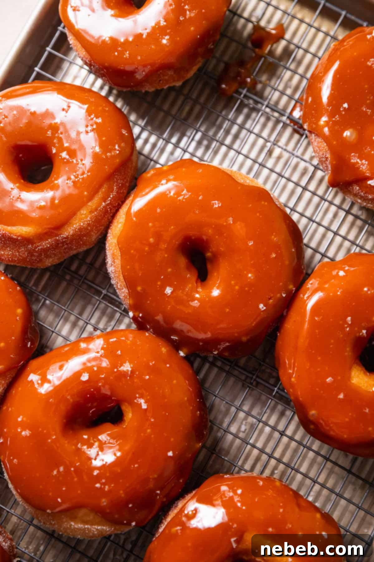 Glistening Salted Caramel Doughnuts 10 A wire rack with salted caramel donuts on top.