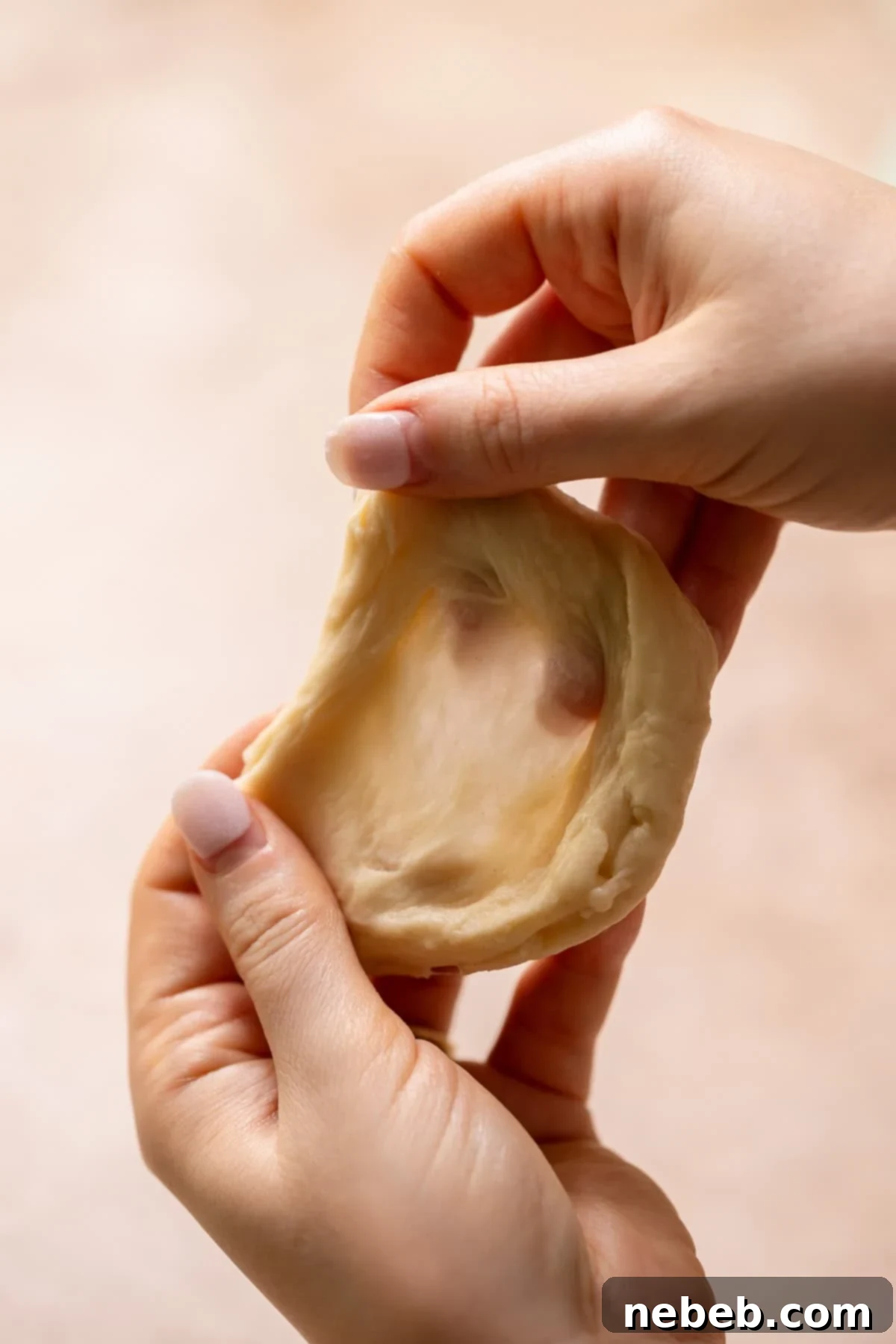 Pillowy Milk Bread Donuts 5 Two hands stretching a piece of donut dough to show the gluten window pane.