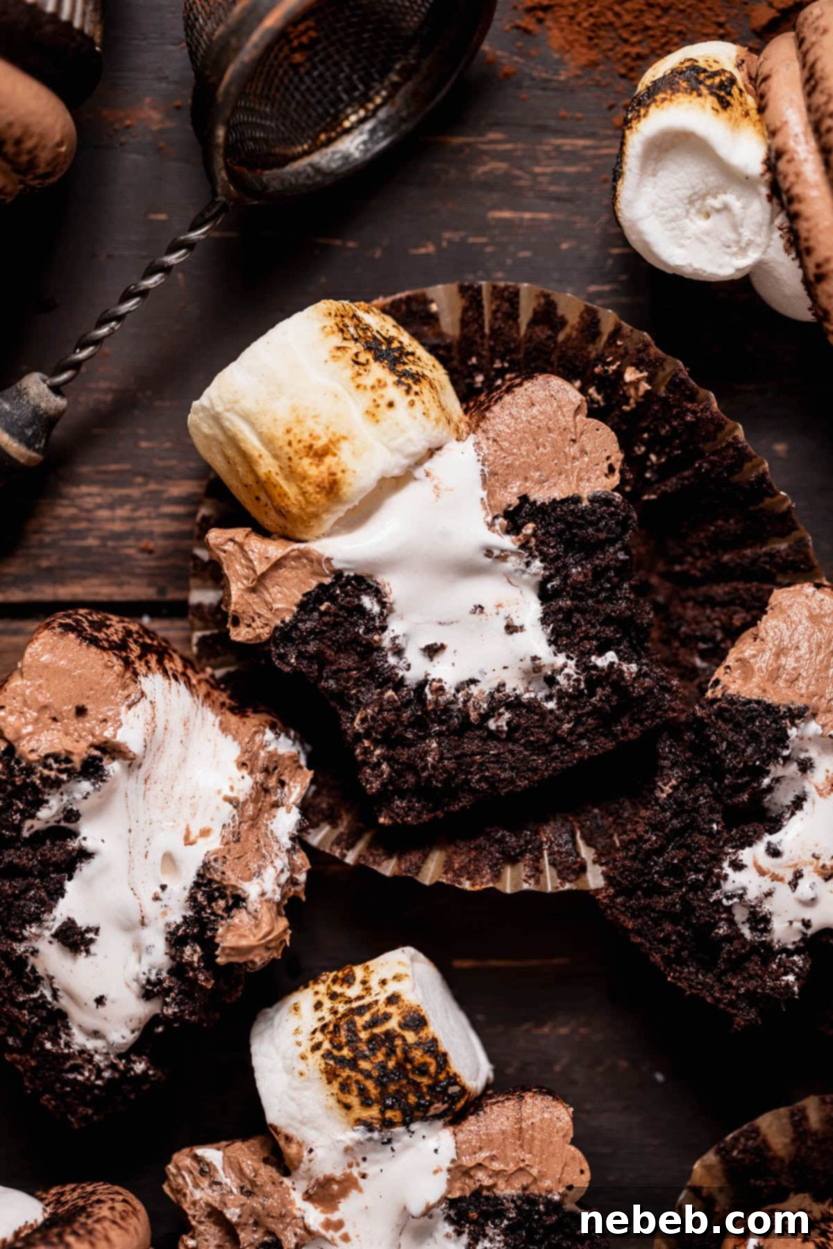 Golden Marshmallow-Stuffed Cocoa Cupcakes 2 Hot cocoa cupcakes with marshmallow filling cut in half to show the filling oozing out, highlighting the moist chocolate cake, fluffy marshmallow center, and creamy frosting.