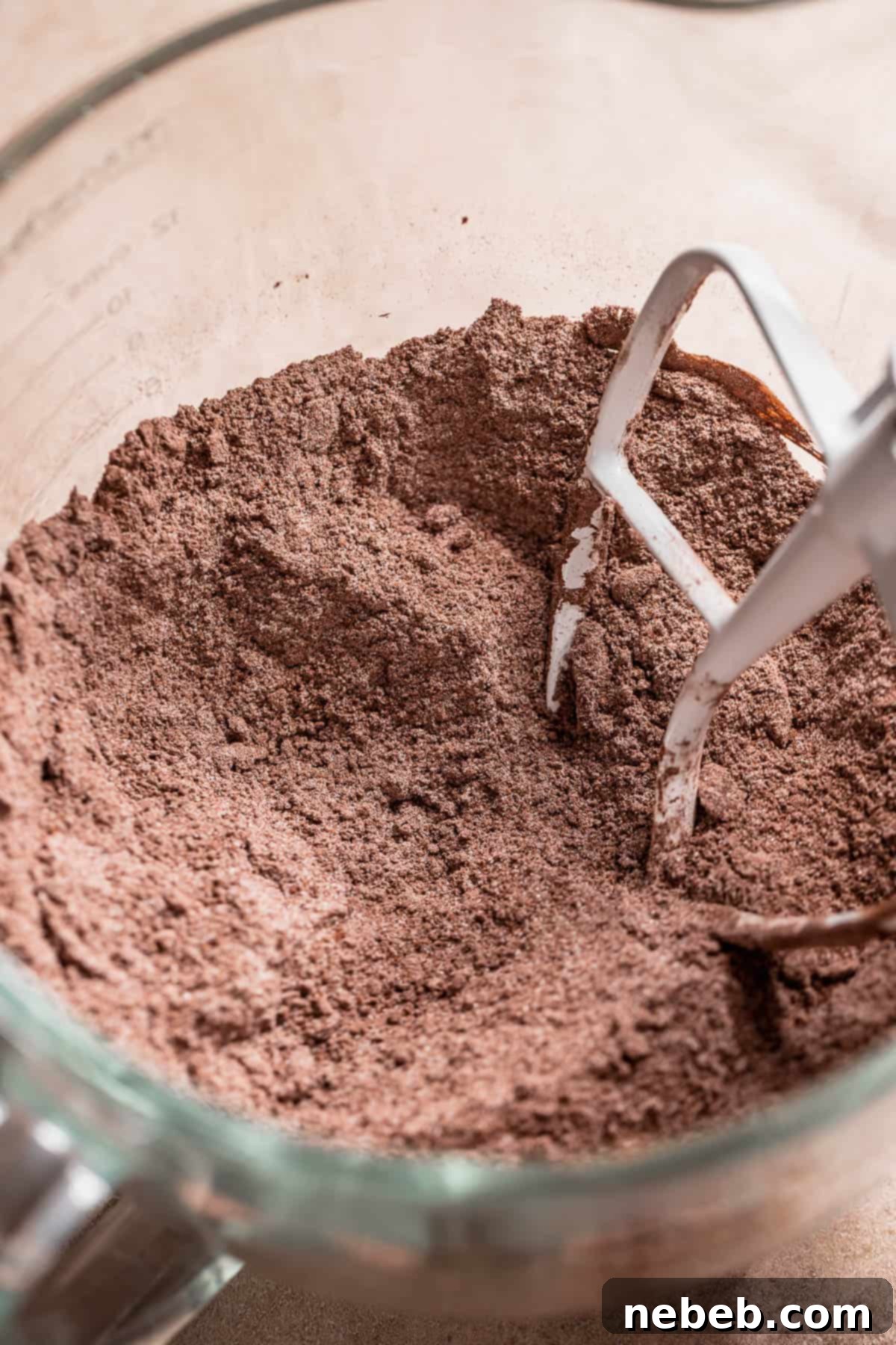 Golden Marshmallow-Stuffed Cocoa Cupcakes 3 A stand mixer bowl showing dry cupcake ingredients and butter mixed together to a crumbly, sandy texture, demonstrating the reverse creaming method for tender chocolate cake.