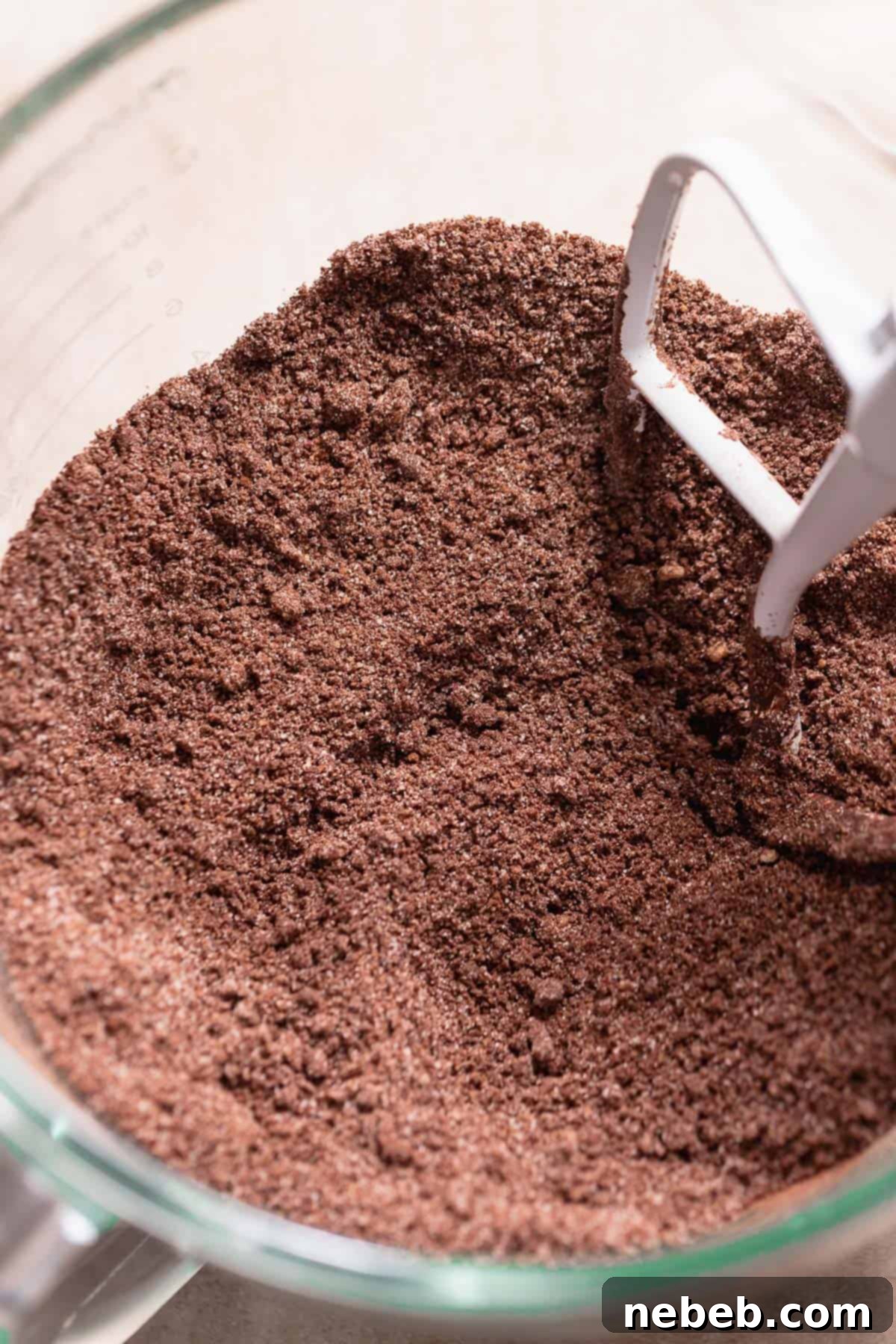 Dry ingredients, including flour, sugar, and cocoa, being mixed with cubed butter in a stand mixer to form fine, sandy crumbs for the chocolate peppermint cupcake batter.