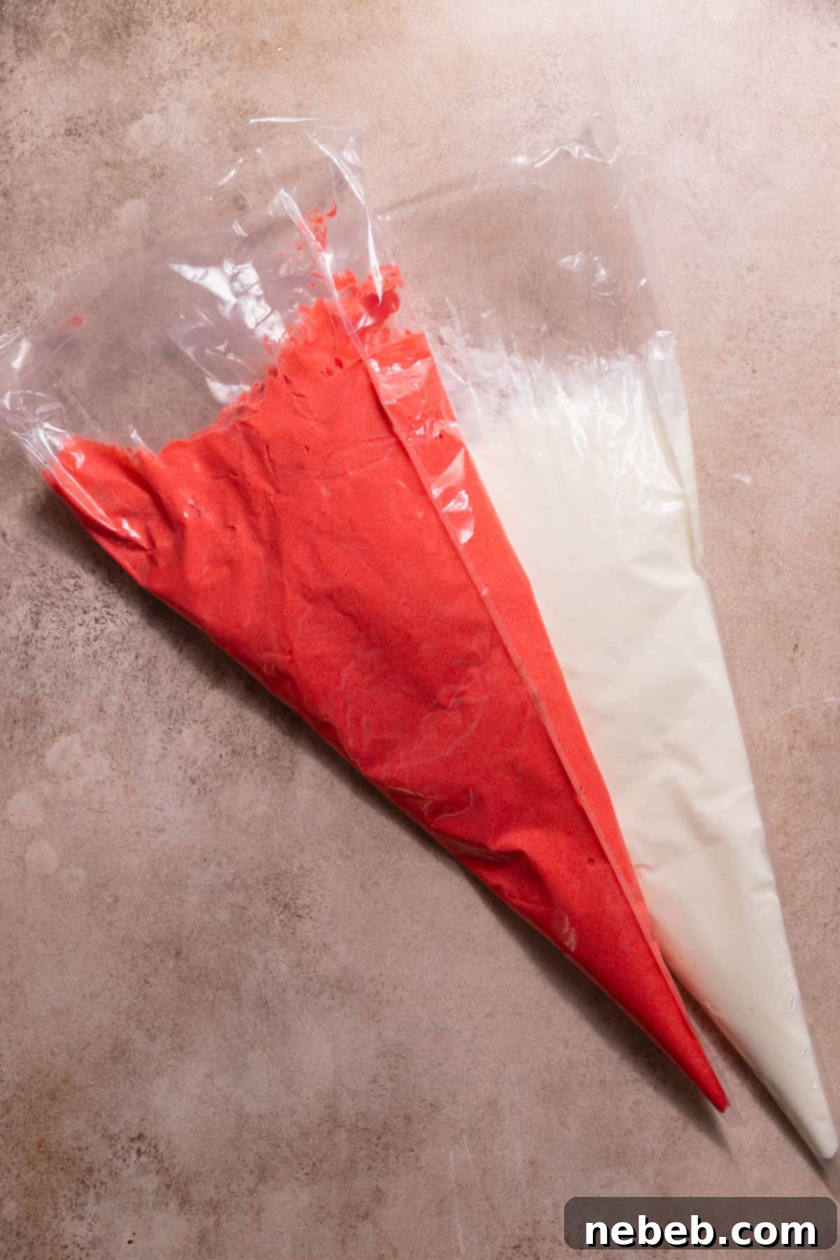 Two piping bags, one filled with pure white peppermint buttercream frosting and the other with vibrant red peppermint buttercream, ready for swirled application on cupcakes.